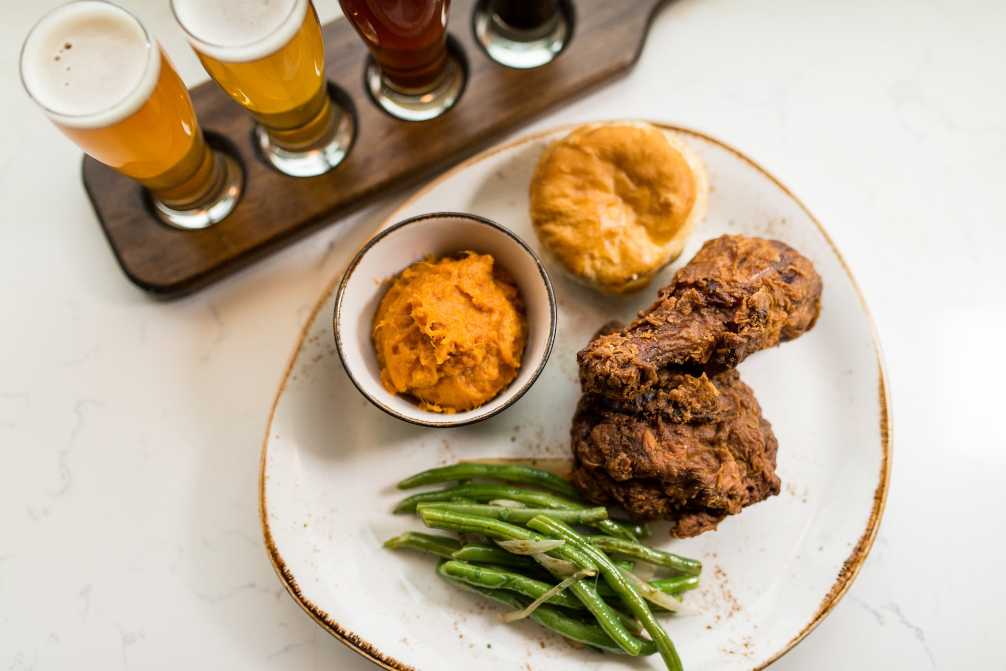Southern fried chicken with molasses biscuit, braised green beans, and sweet potato mash and a local beer flight at Chicken + Beer. / Photo credit- Mia Yakel.