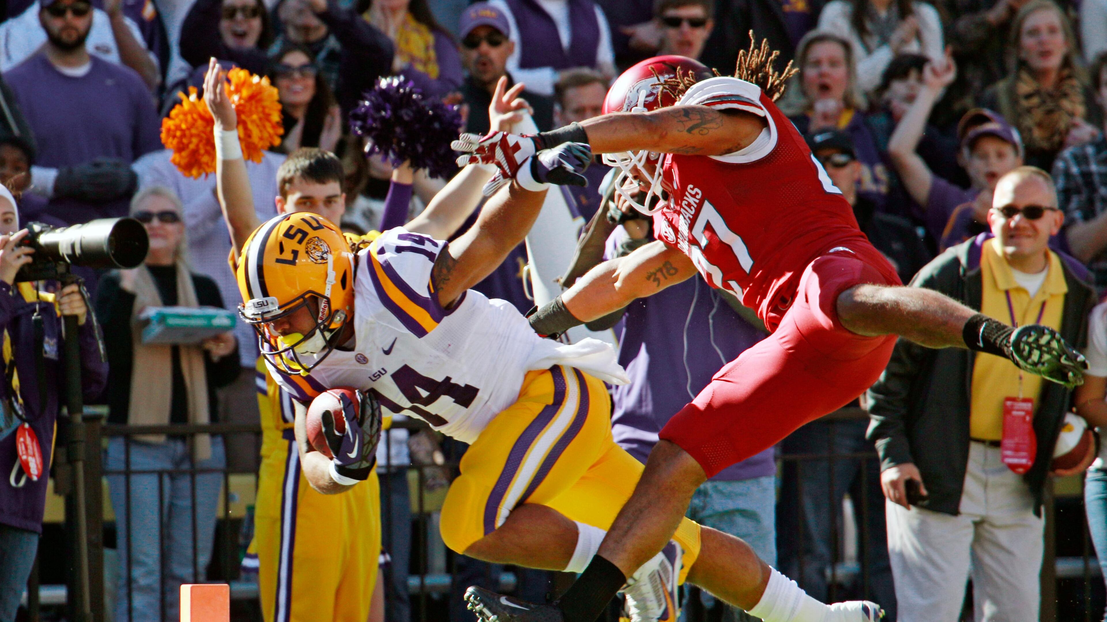 LSU running back Terrence Magee (14) gets into the end zone in front of Arkansas safety Alan Turner (27) for a touchdown in the first half of an NCAA college football game in Baton Rouge, La., Friday, Nov. 29, 2013. (AP Photo/Bill Haber)