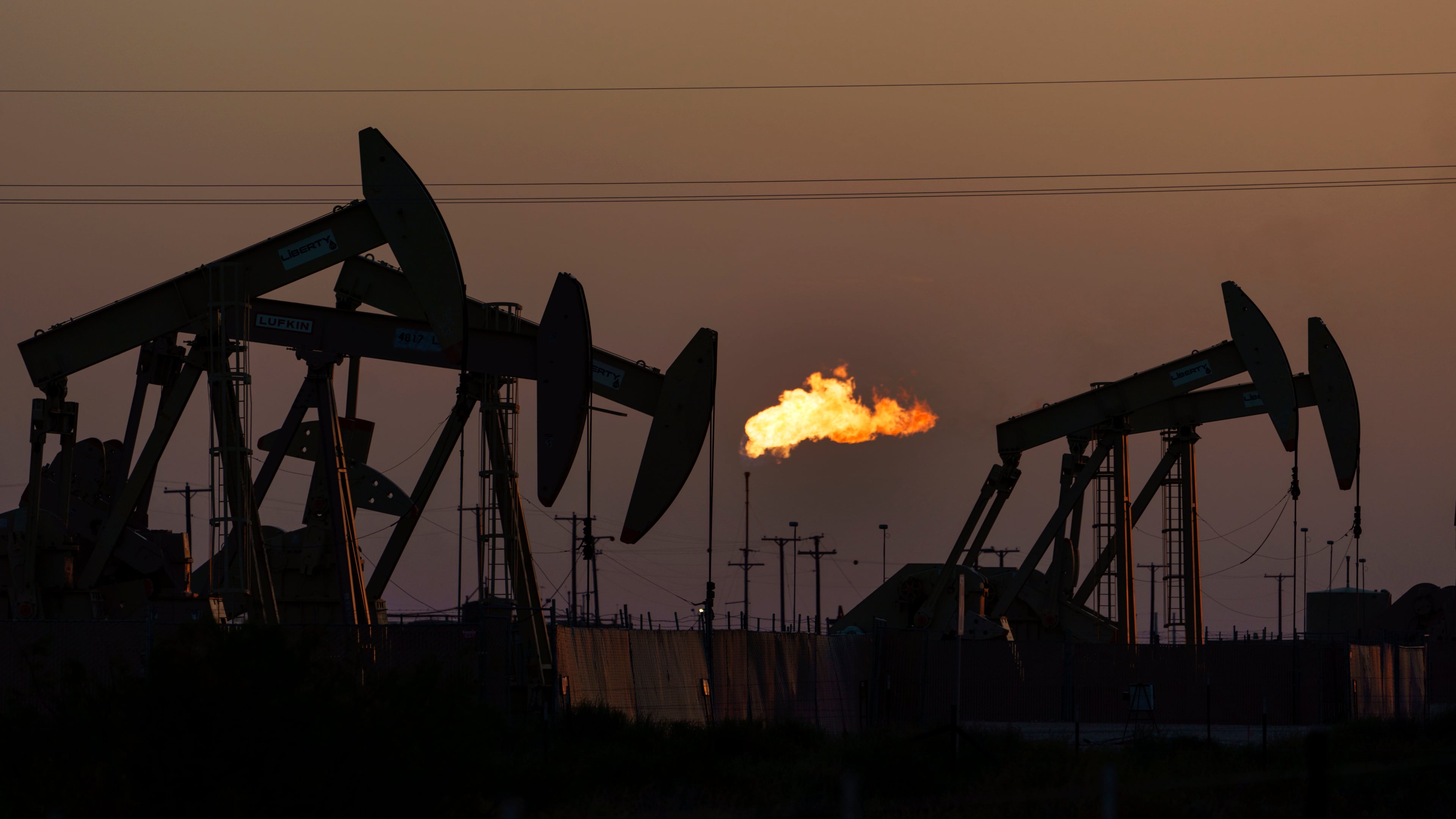FILE - A flare burns off methane and other hydrocarbons as oil pumpjacks operate in the Permian Basin in Midland, Texas, on Oct. 12, 2021. (AP Photo/David Goldman, File)