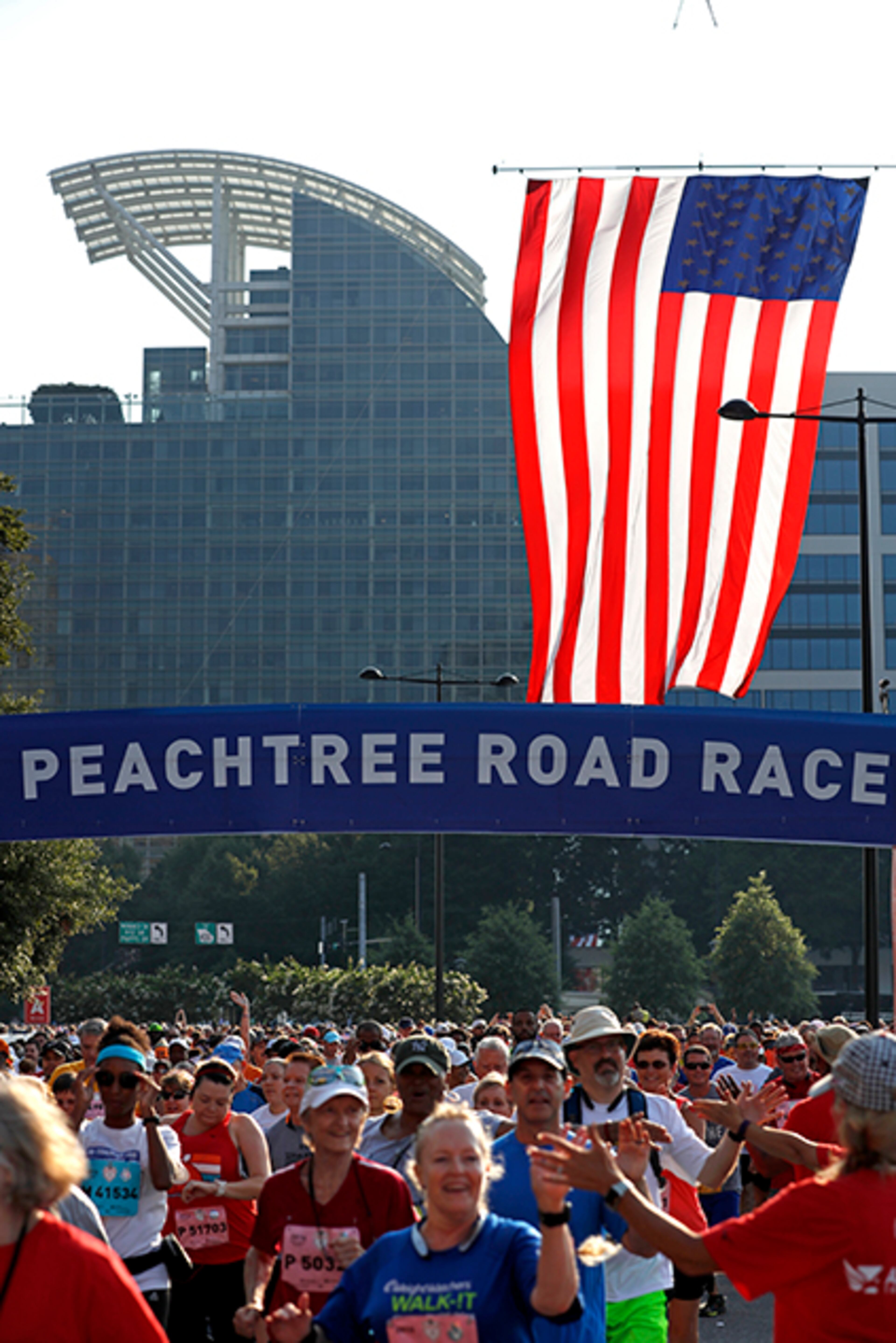 The U.S. flag flies over the starting line as runners begin the 47th AJC Peachtree Road Race at Lenox Square Monday, July 4, 2016, in Atlanta.