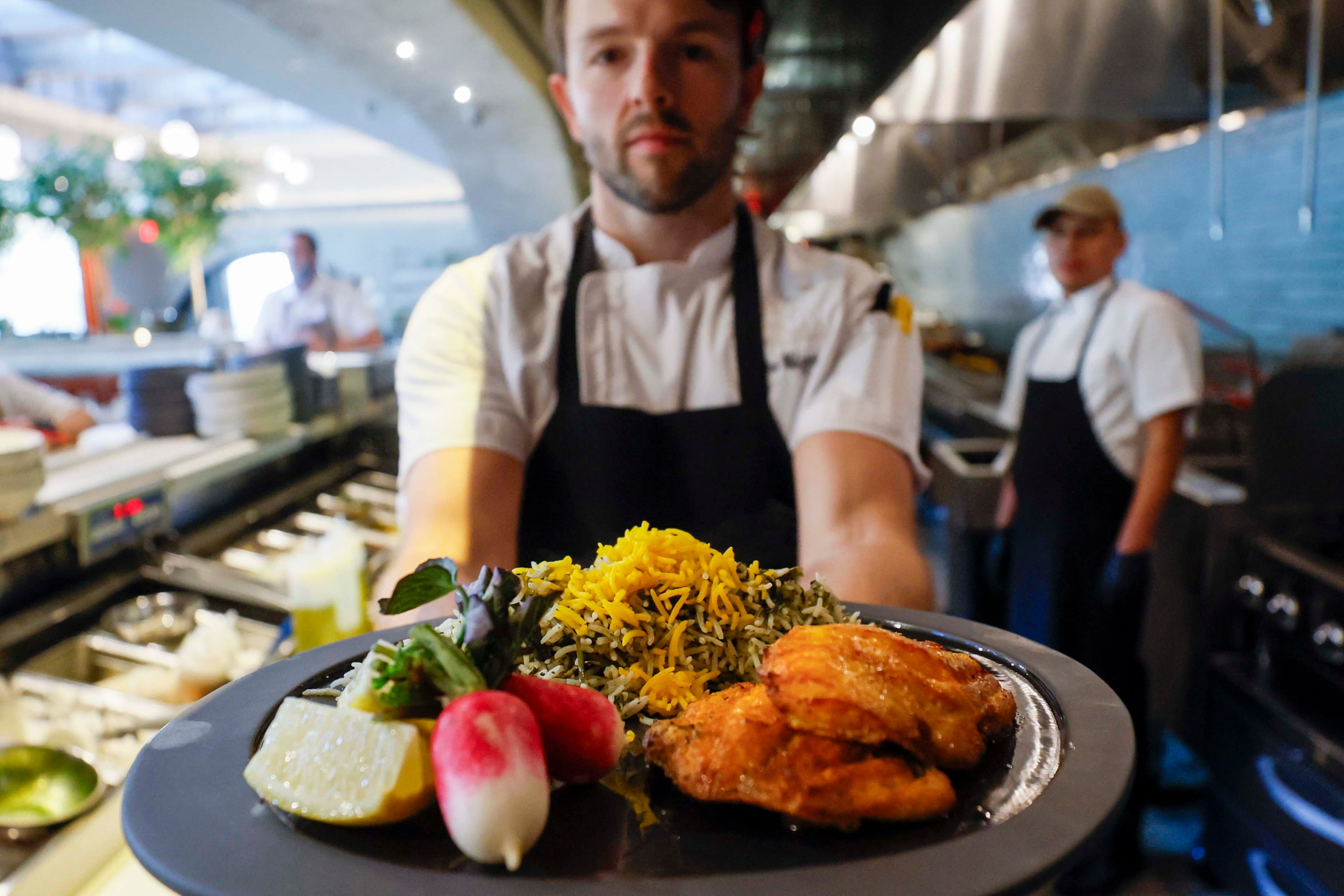 Drew Metzger, senior director of culinary at Rumi’s Kitchen, presents a mahi sabzi polo, a traditional signature dish for Nowruz (Persian New Year), symbolizing springtime renewal on Sunday, March 22, 2026. (Miguel Martinez/AJC)