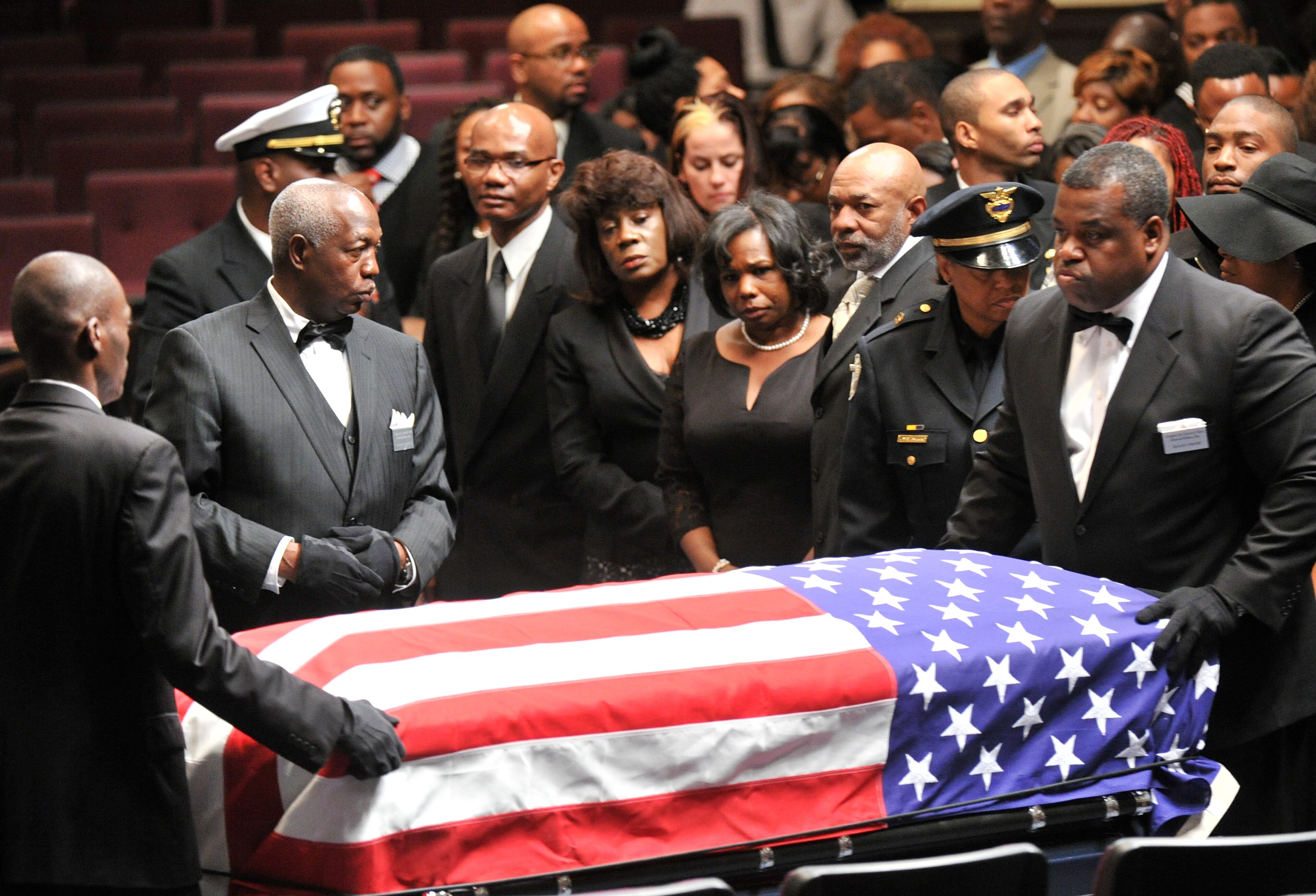 The casket is carried by funeral staff as APD Officer Shawn Smiley's mother Carol Smiley (center left) and wife Terra Smiley (center right) look during APD Officer Shawn Smiley's funeral at First Baptist Church of Atlanta on Saturday, November 10, 2012. APD Officer Shawn Smiley was in the passenger seat last weekend when an APD helicopter searching for a missing 9-year-old boy crashed in Atlanta. HYOSUB SHIN / HSHIN@AJC.COM
