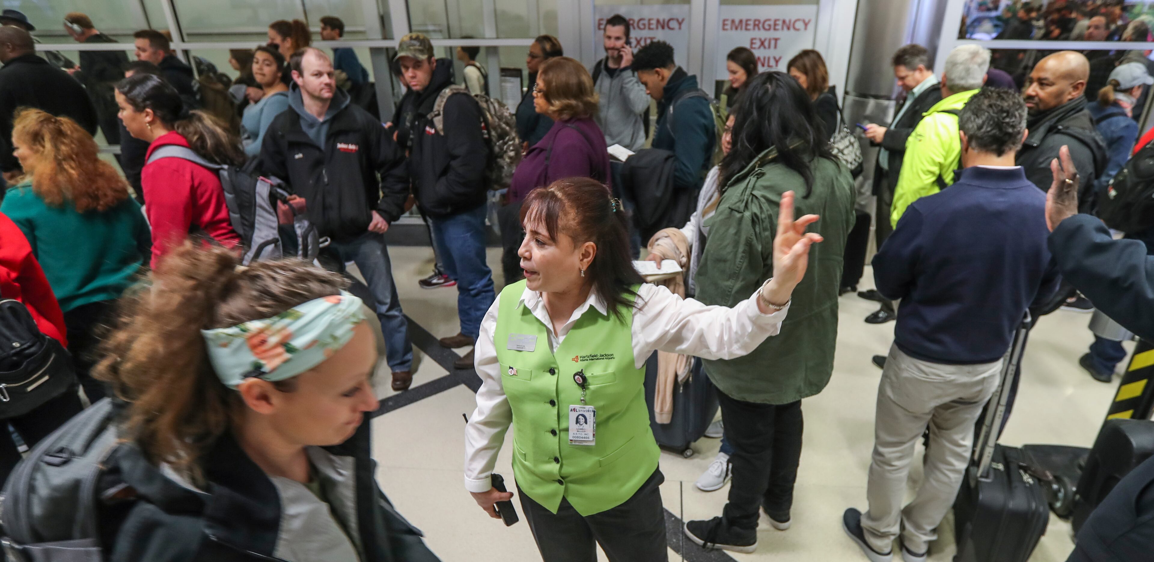 January 14, 2019 Atlanta: Customer Service's Magda Lambo (center) directs travelers as security lines at Hartsfield-Jackson International Airport stretched more than an hour long Monday morning, Jan. 14, 2019 causing travelers to miss flights amid the partial federal shutdown. At a time when the worlds busiest airport has its biggest crowds, there were at least six security lanes closed at domestic terminal security checkpoints, while passengers waited in lines that stretched through the terminal and were winding through baggage claim. The long lines signaled staffing shortages at security checkpoints, as TSA officers have been working without pay since the federal shutdown began Dec. 22. Airport officials normally advise travelers to get to the airport two hours before domestic flights, but on Monday morning Hartsfield-Jackson spokesman Andrew Gobeil advised that travelers should consult with their airlines. Travelers may need to get to the airport even earlier due to the long waits. JOHN SPINK/JSPINK@AJC.COM