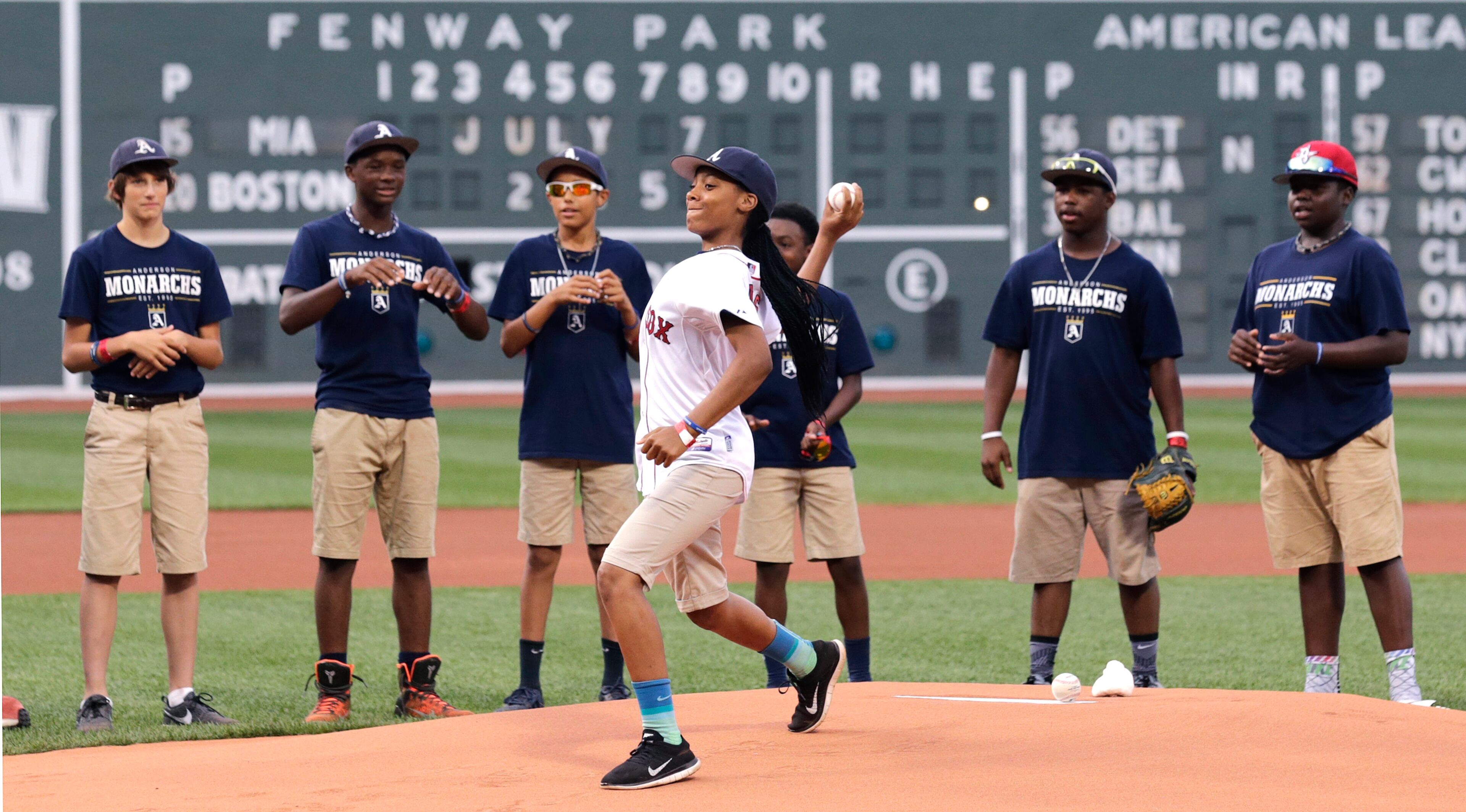 Mo'ne Davis, heroine of the 2014 Little League World Series, throws out the ceremonial first pitch with her teammates from the Anderson Monarchs watching prior to a baseball game between the Boston Red Sox and Miami Marlins at Fenway Park in Boston, Tuesday July 7, 2015. (AP Photo/Charles Krupa)