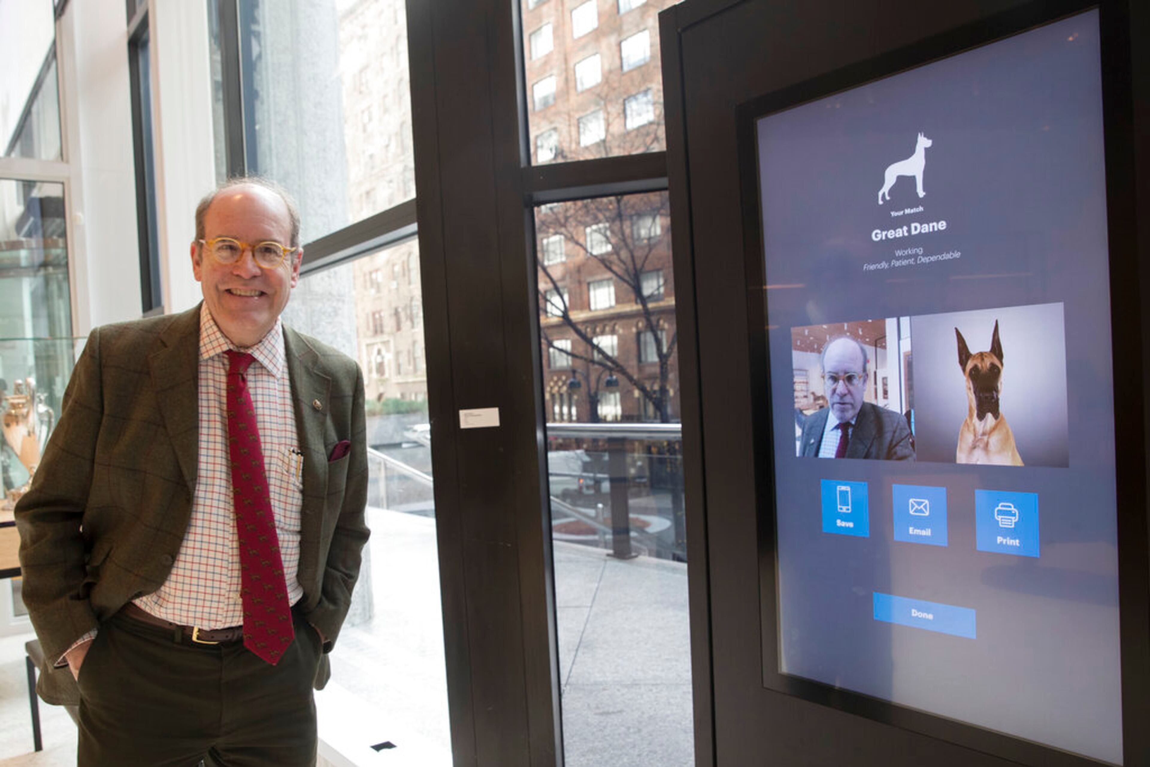 This Wednesday, Jan. 9, 2019, photo shows American Kennel Club Museum of the Dog's Executive Director Alan Fausel smiling after finding his dog breed match at the Find Your Match interactive kiosk during a tour of the museum in New York. The museum opens Feb. 8. (AP Photo/Mary Altaffer)