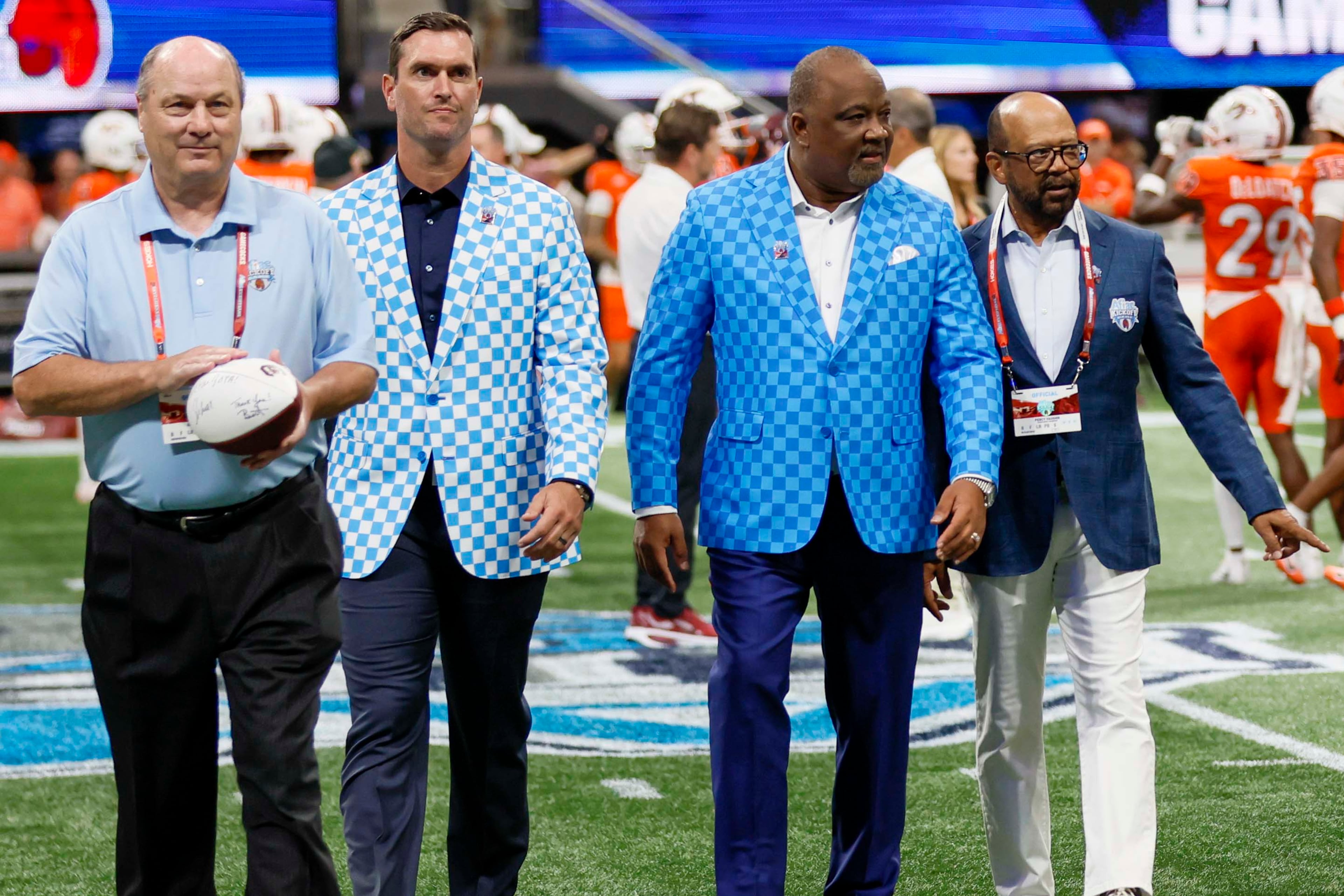 Gary Stokan (from left), Aflac Senior Vice President of Group Voluntary Benefits Bob Ruff, Aflac President Virgil Miller and Peach Bowl Chairman Percy Vaughn walk off the field after the coin toss just before the Aflac Kickoff Game between South Carolina and Virginia Tech at Mercedes-Benz Stadium on Aug. 31. (Miguel Martinez/AJC)