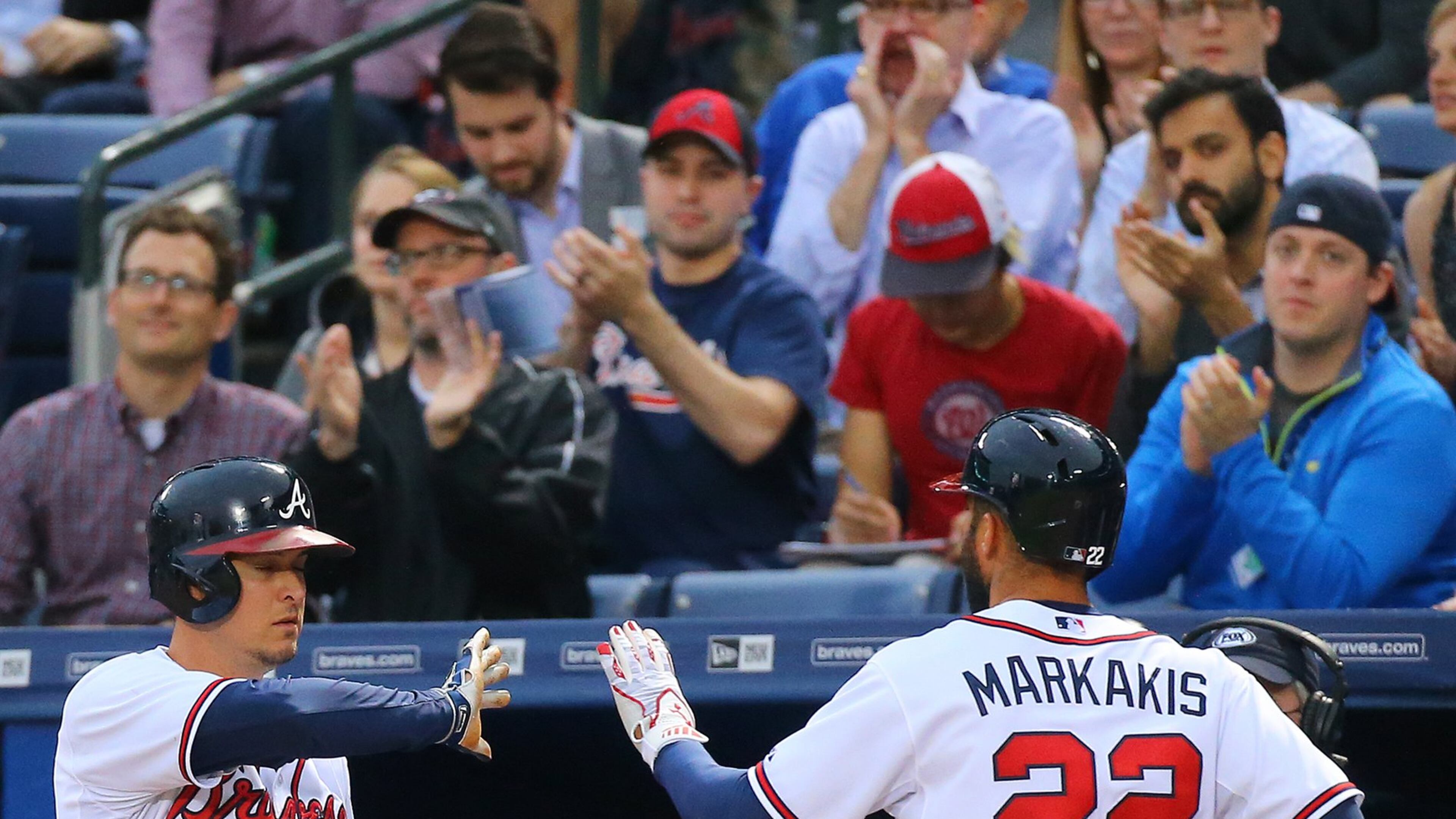Braves fans applaud as Nick Markakis greets Kelly Johnson after scoring on a double by Alberto Callaspo to take a 2-1 lead over the Nationals during the first inning of a baseball game on Tuesday, April 28, 2015, at Turner Field. (Curtis Compton / ccompton@ajc.com)