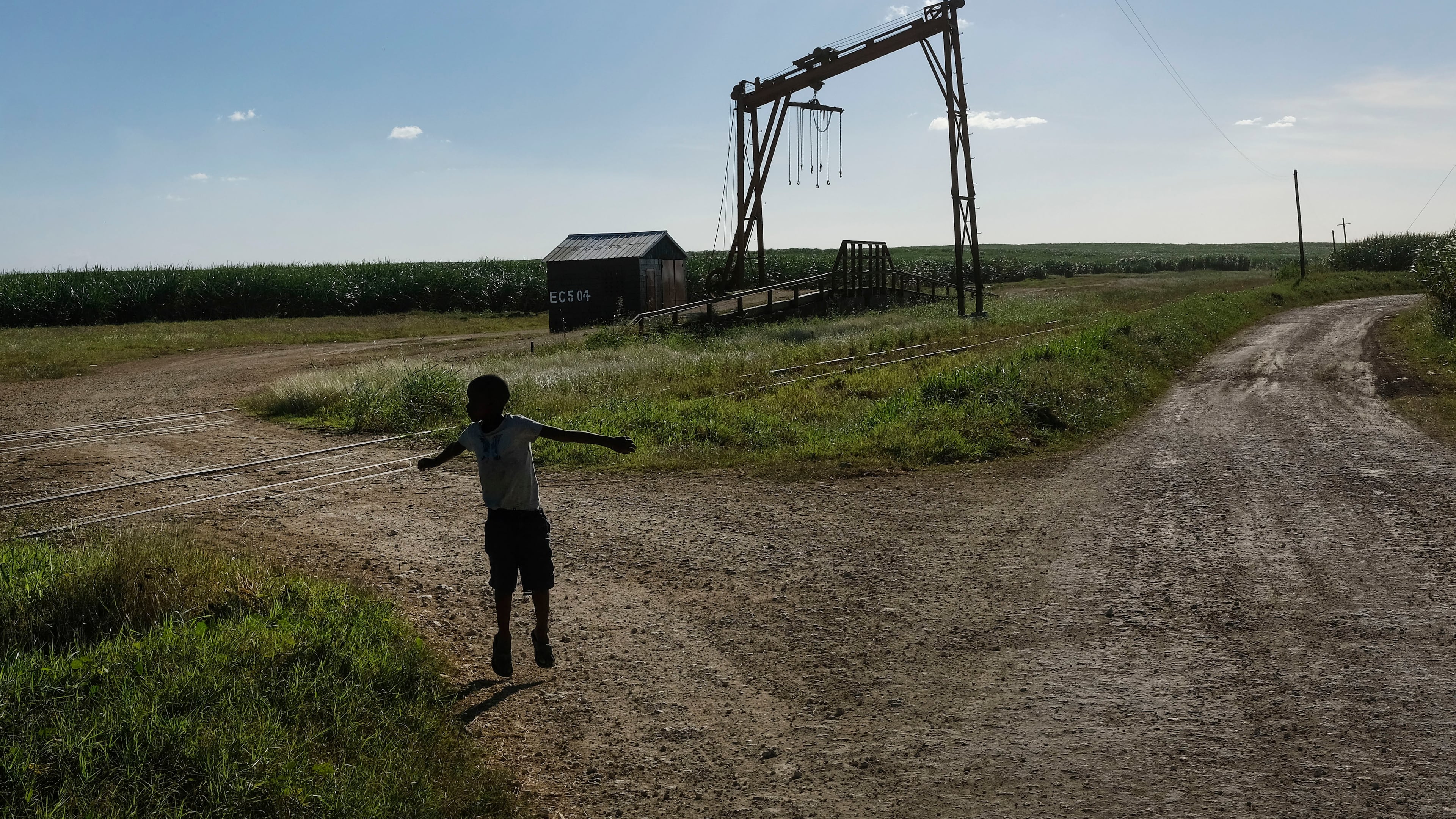 FILE - A youth plays near the machine where the sugar cane is weighed in the Lima batey, or neighborhood, in La Romana, where Central Romana Corporation, Ltd. operates its sugar operations in Dominican Republic, Nov. 17, 2021. (AP Photo/Matias Delacroix, File)