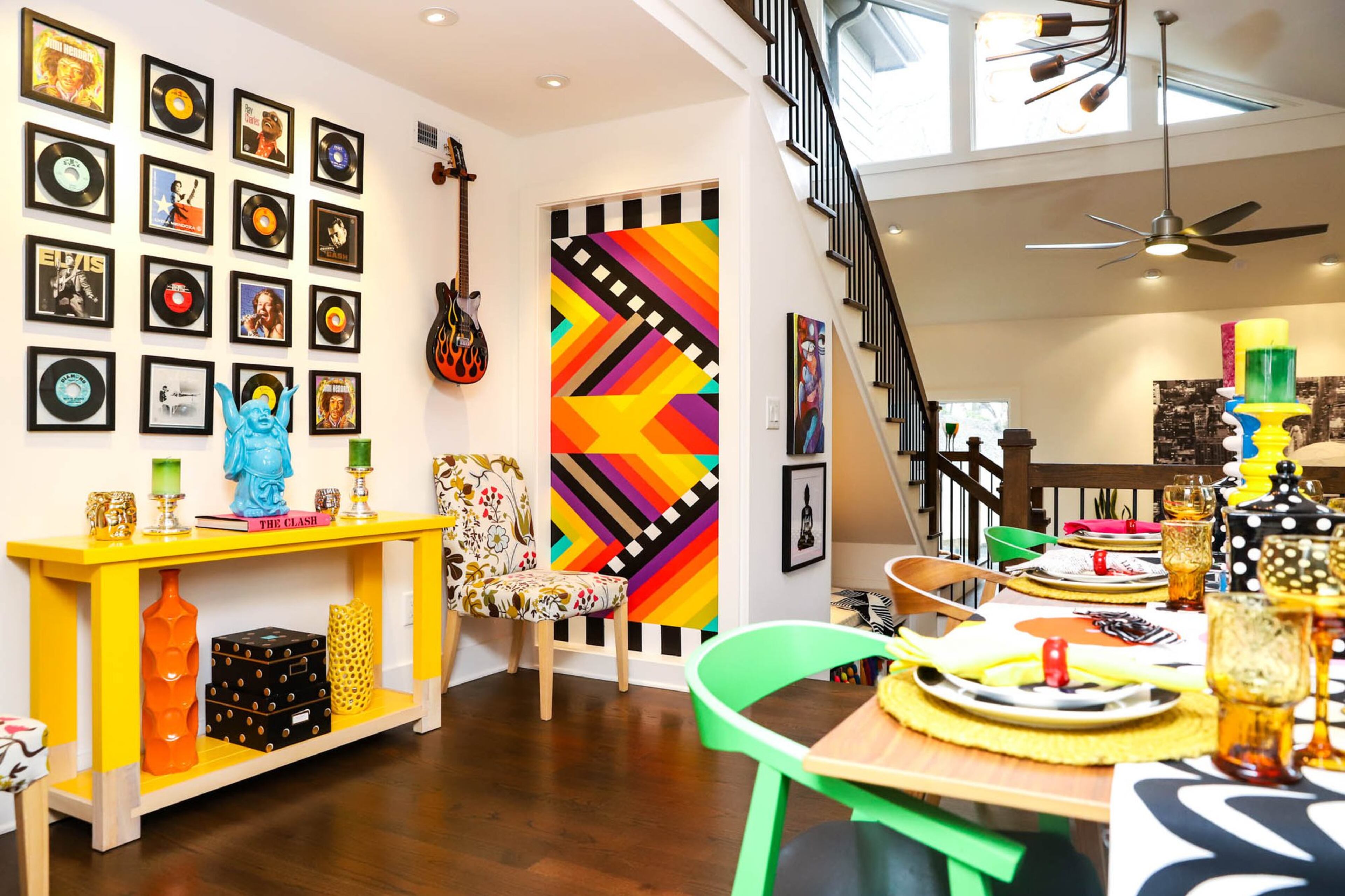 A wall of music memorabilia covers one wall of Jeff and Paola Roder’s dining room. Records that they found in storage in a home they owned in Philadelphia mixed with art from the Music Icons series of stamps from the U.S. Postal Service creates a gallery wall. To the right of the gallery wall is a wall that Paola painted in vivid stripes to enhance the modern pop art vibe of their decor. Text by Shannon Dominy. Photo by Reynolds Rogers.