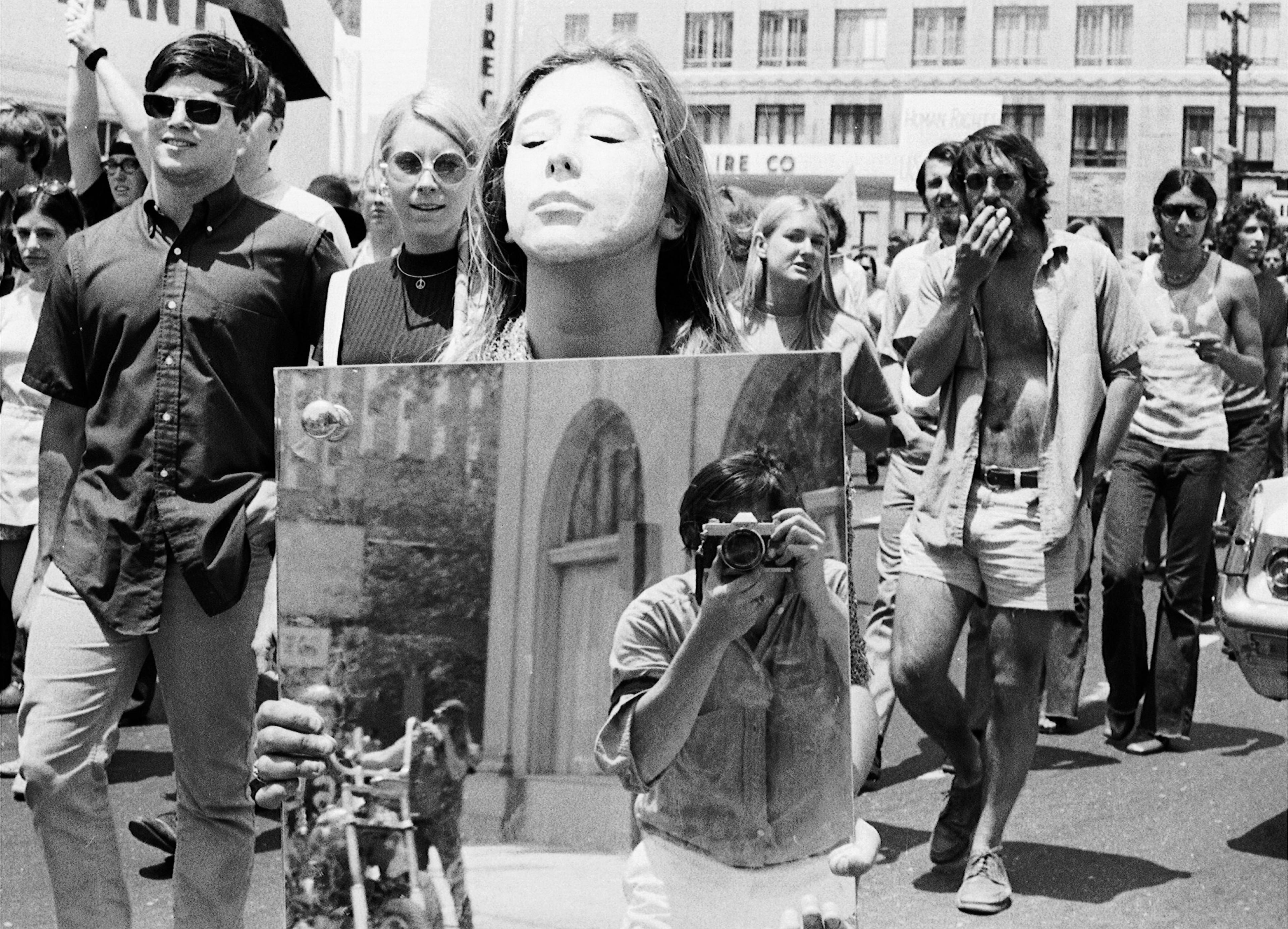 Boyd Lewis, the photographer, is captured in a mirror carried by a protester in a street demonstration, one of many that he covered.
