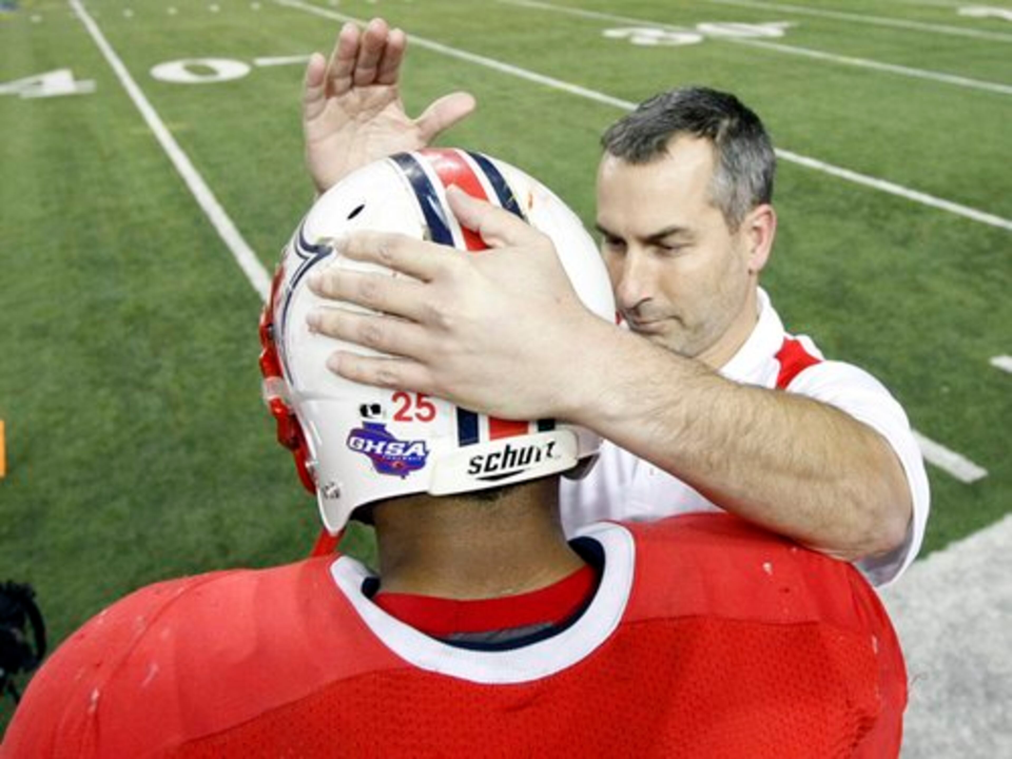 Sandy Creek Fighting Patriots head coach Chip Walker pats running back # 25 Rajion Neal on the helmet for a job well done.