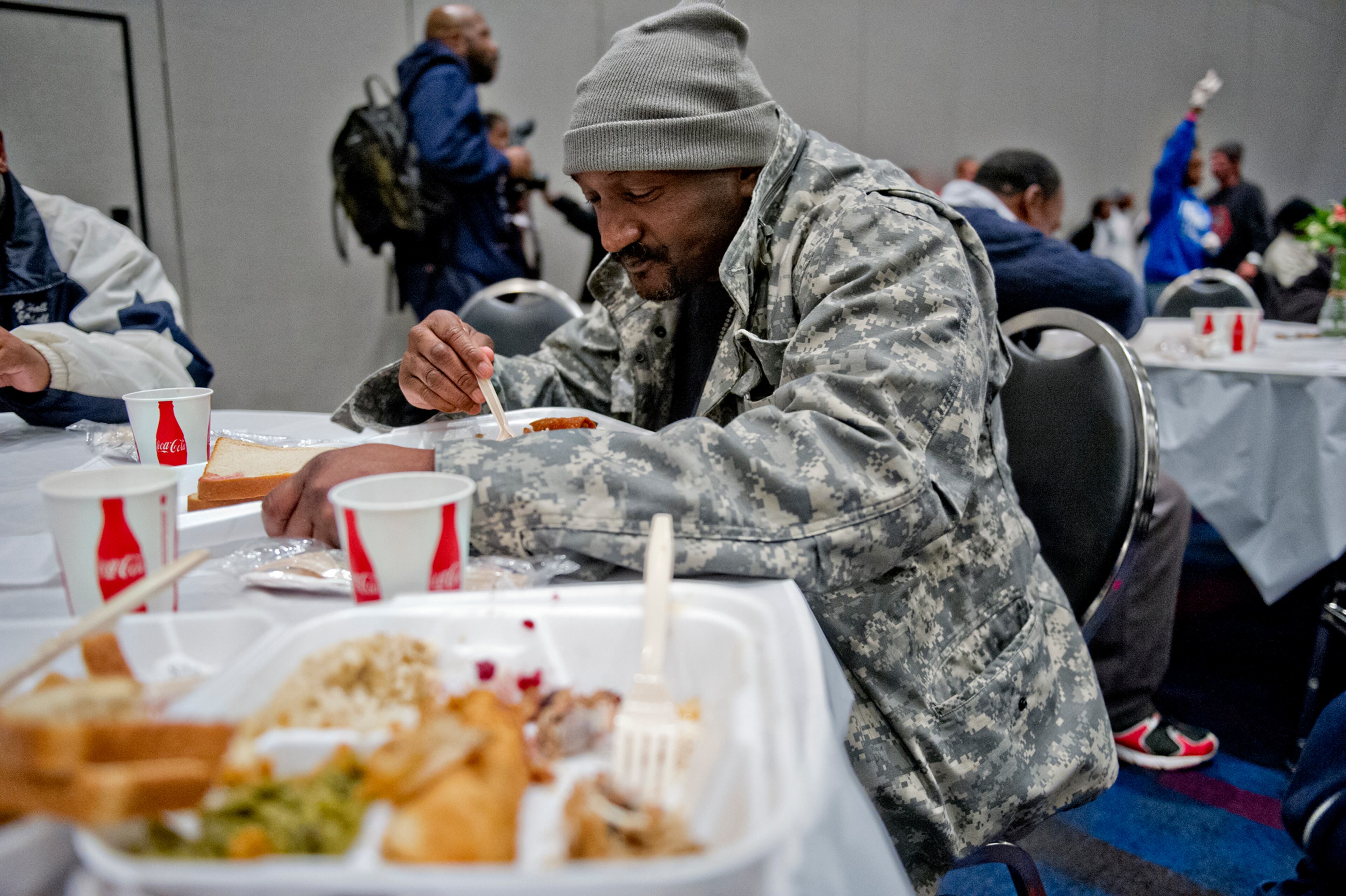 Louis McClure Jr. (center) takes a bite of his meal during the 44th annual Hosea Feed the Hungry and Homeless Thanksgiving Holiday Dinner at the Georgia World Congress Center.