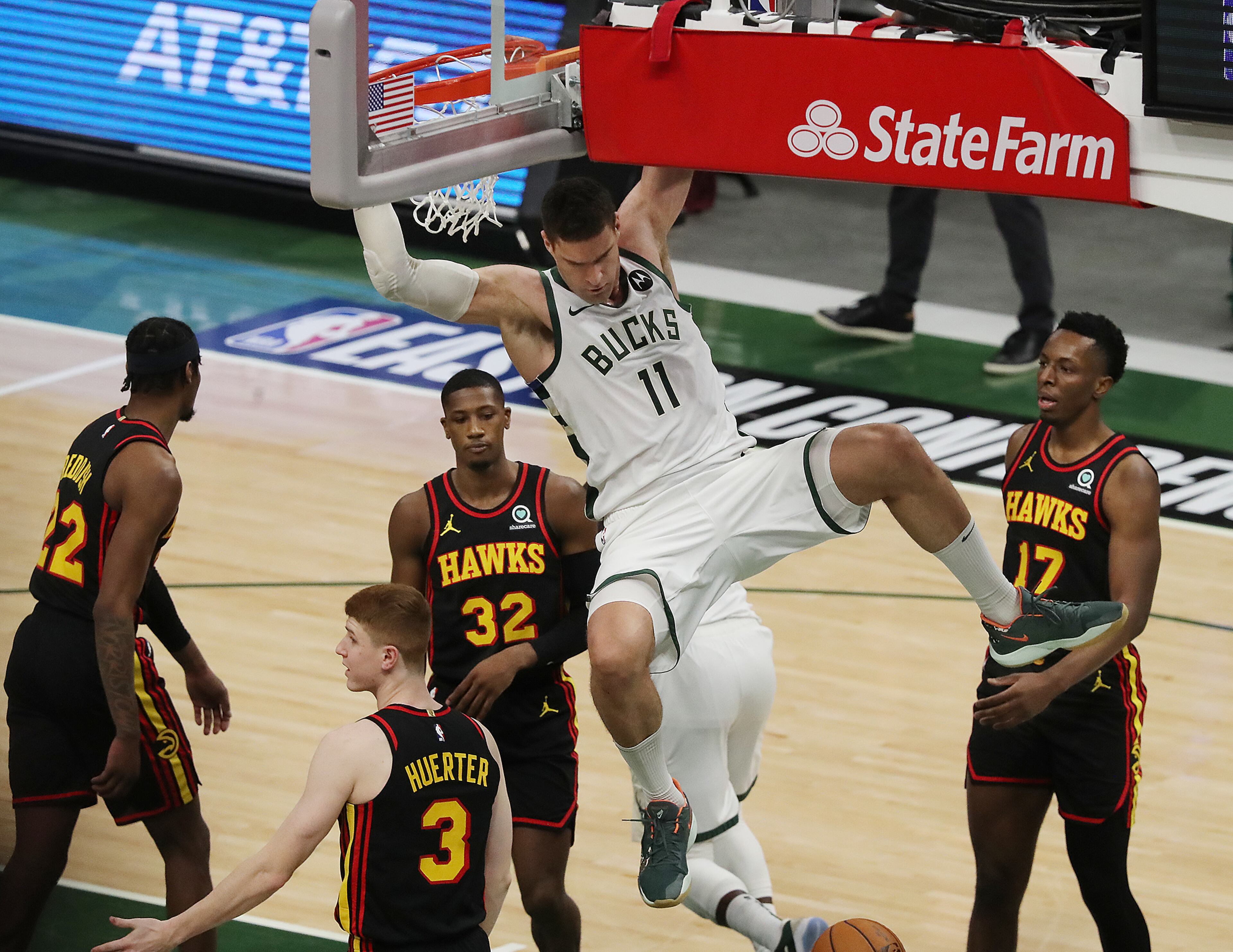 Milwaukee Bucks center Brook Lopez hangs onto the basket after slamming for two against Atlanta Hawks defenders during the first quarter in game 5 of the NBA Eastern Conference Finals on Thursday, July 1, 2021, in Milwaukee. “Curtis Compton / Curtis.Compton@ajc.com”