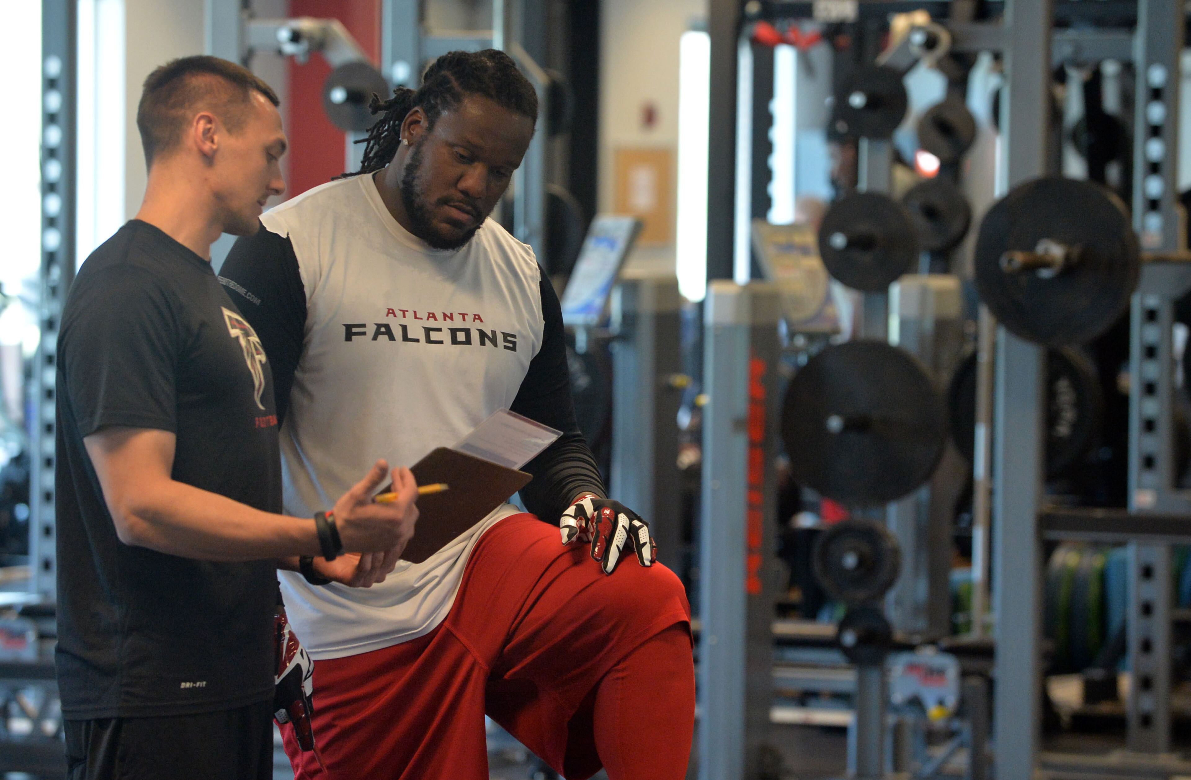 Assistant strength coach Jonas Beauchemin, in his third season with the Falcons, goes over numbers with defensive tackle Jonathan Babineaux during a workout in the weight room at the team's headquarters in Flowery Branch on Tuesday, April 22, 2014.
