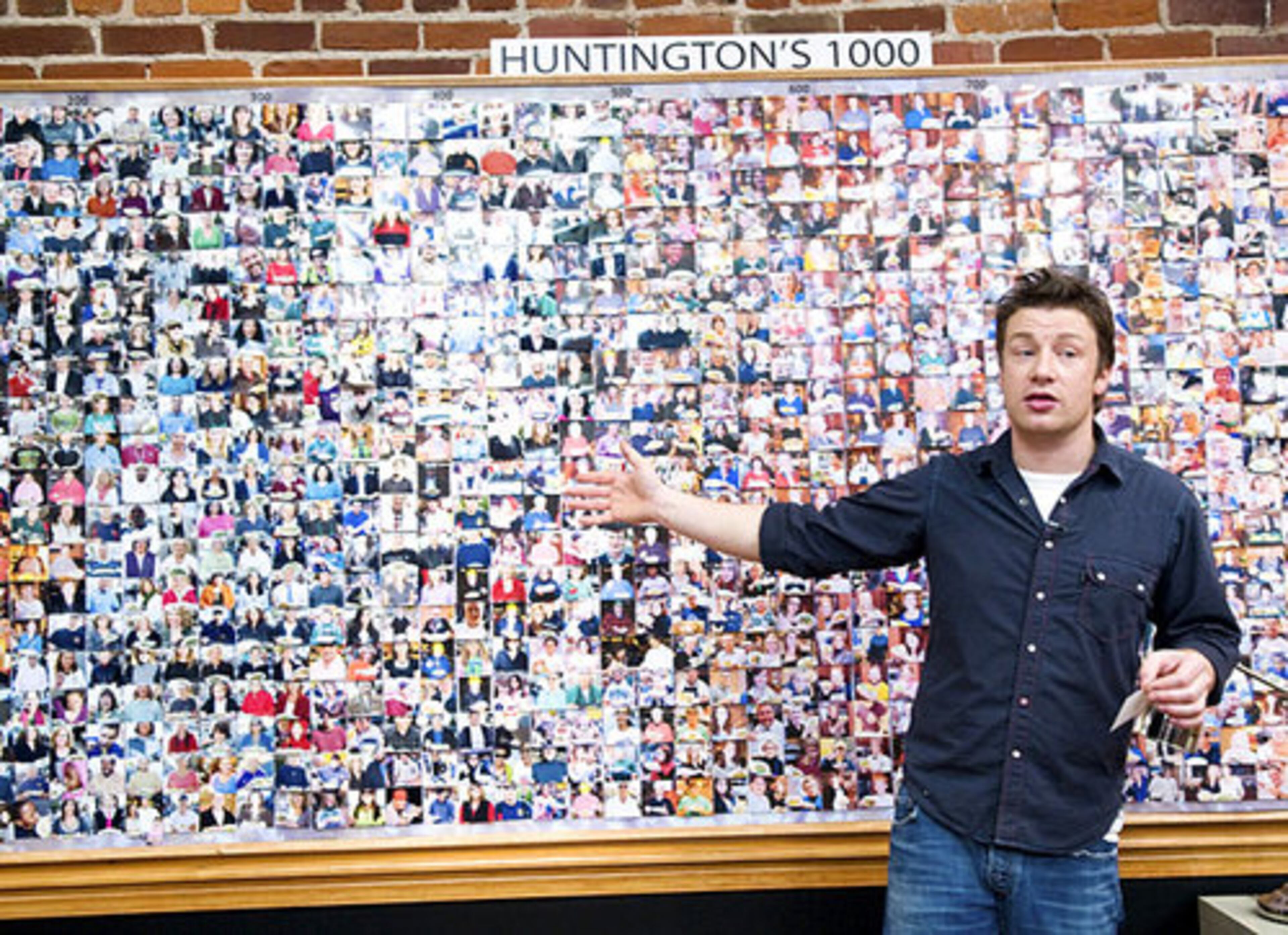 Chef and TV personality Jamie Oliver stands in front of a board with photos of residents of Huntington, W. Va., during the taping of his reality series, "Jamie Oliver's Food Revolution." The show airs Friday on ABC.