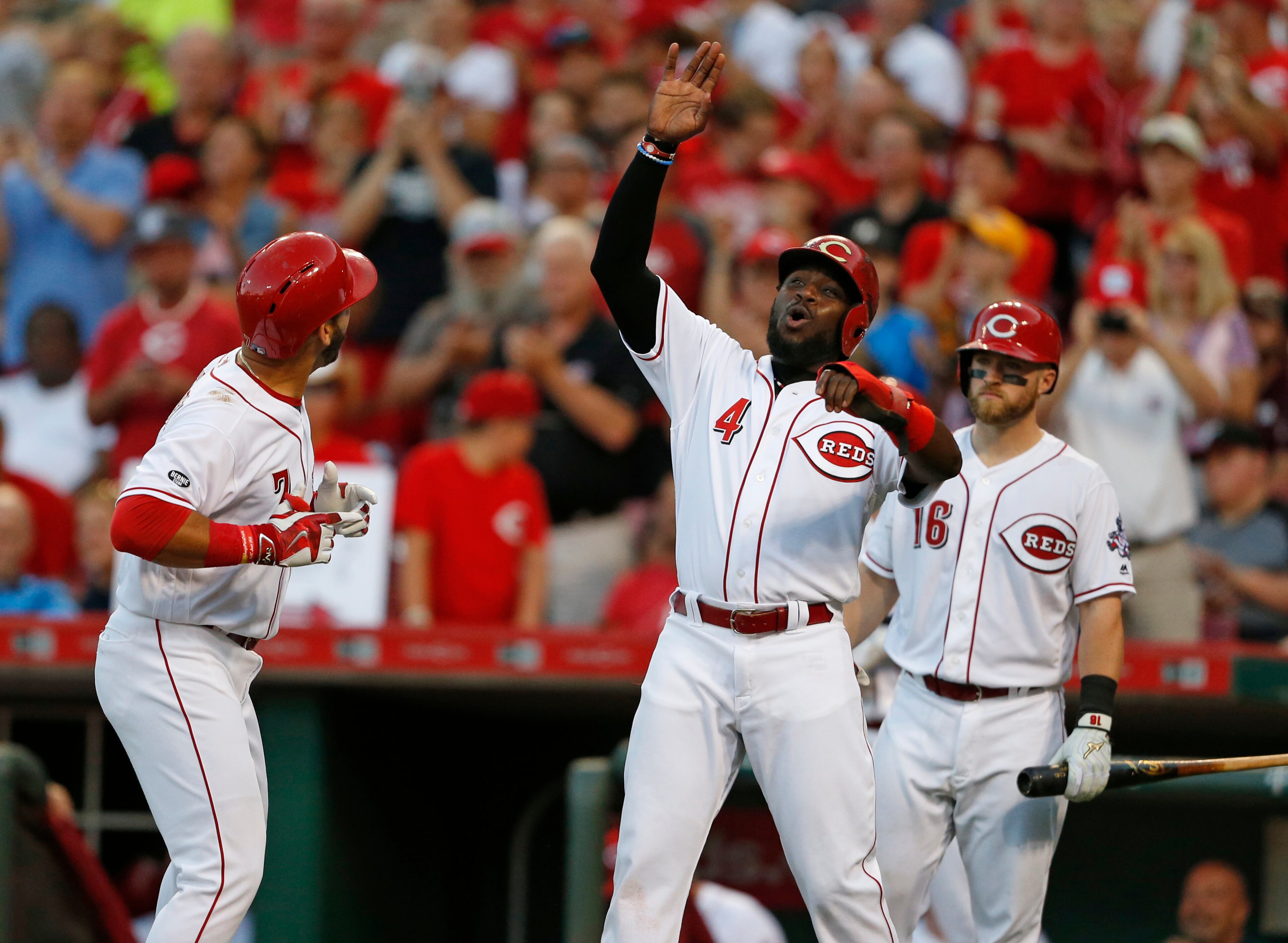 Cincinnati Reds' Brandon Phillips (4) reacts to a two-run homer by Eugenio Suarez, left, off Atlanta Braves starting pitcher Matt Wisler during the fourth inning of a baseball game, Monday, July 18, 2016, in Cincinnati. Tucker Barnhart is at right. (AP Photo/Gary Landers)