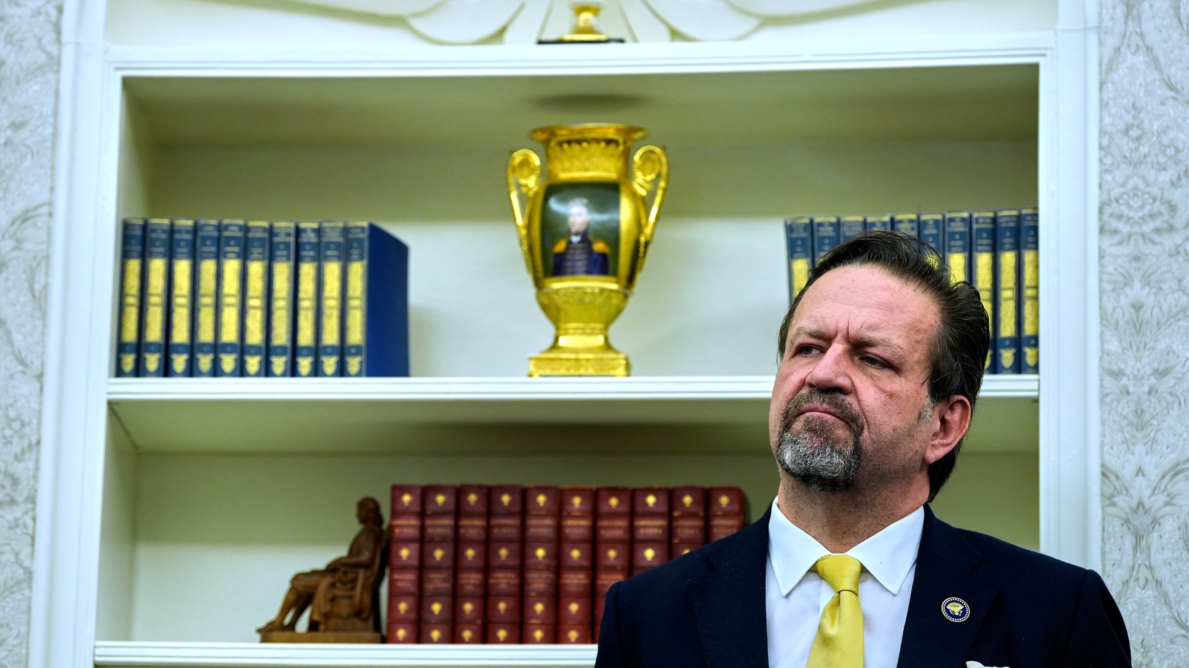 FILE - Sebastian Gorka listens as President Donald Trump speaks with reporters after signing executive orders in the Oval Office of the White House, April 23, 2025, in Washington. (AP Photo/Alex Brandon, File)