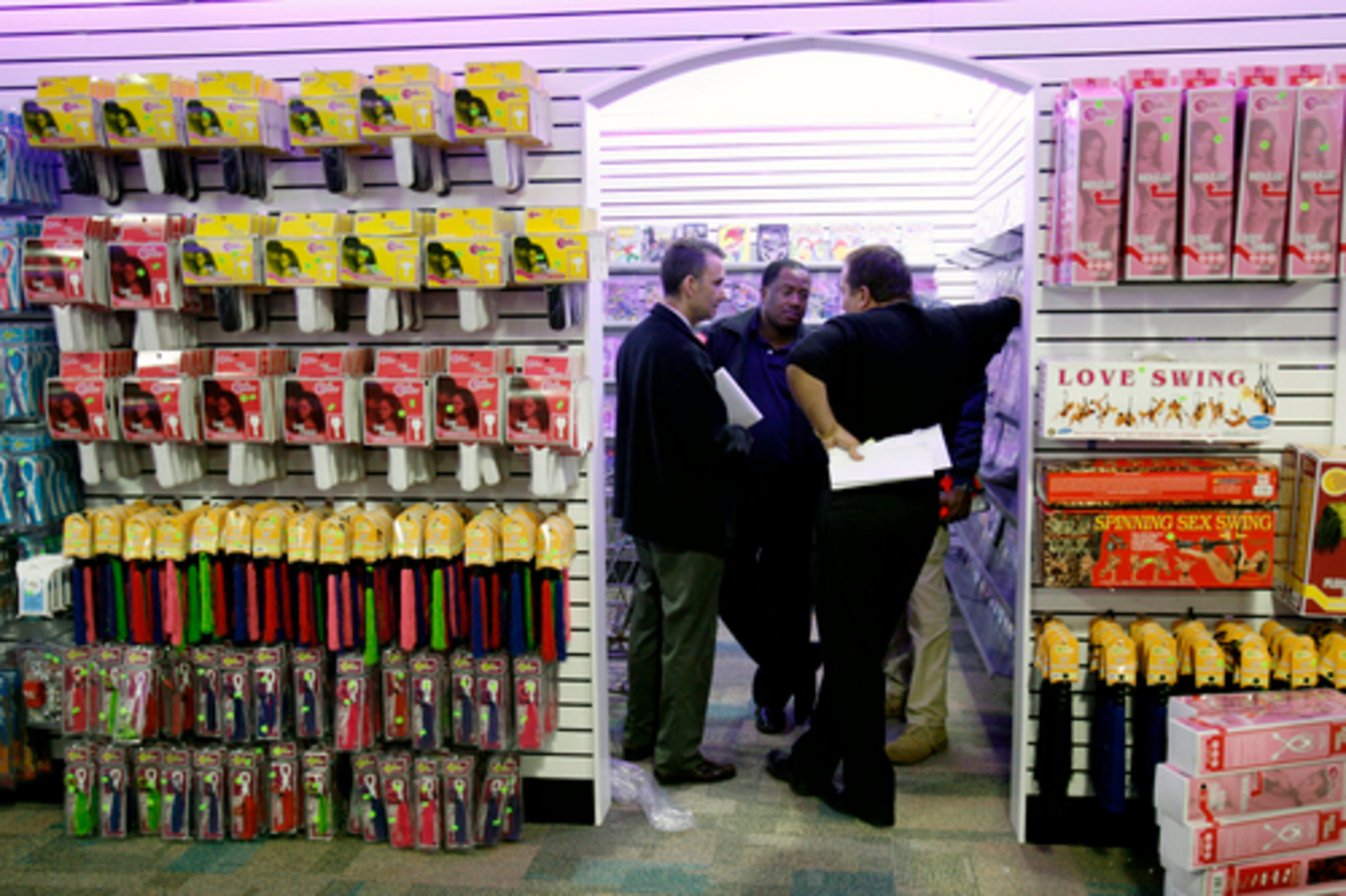 In December 2006, Federal District Judge Tom Thrash ruled the Love Shack was operating illegally if it didn't reduce the amount of adult merchandise. The county interpreted the judge's order to mean it could shut the Johns Creek shop down. The county did not though. In the photo, Cornetta huddles with an inspector from the county.