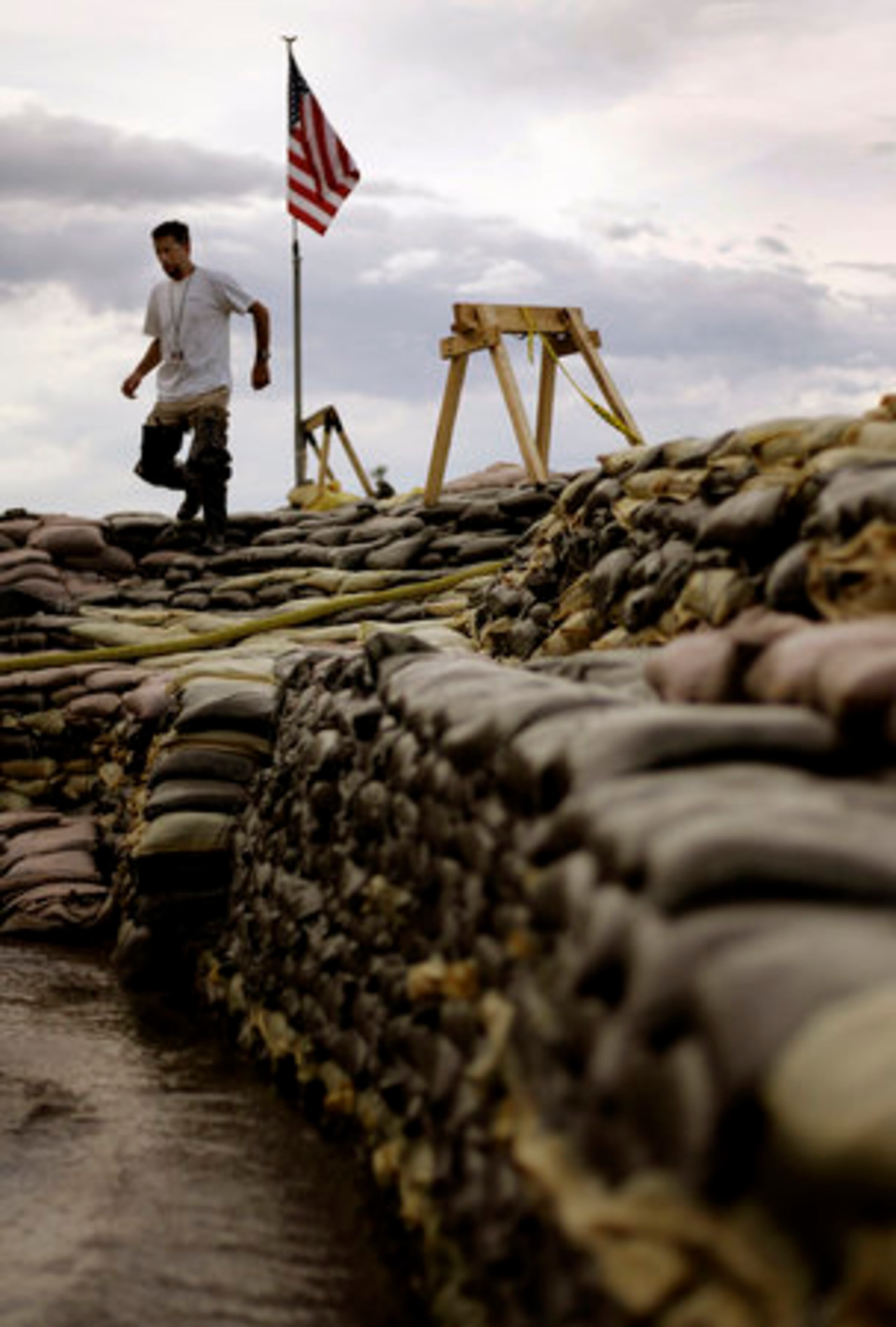 Rick Yeomans walks atop a massive wall of sandbags in Clarksville, Mo. that is holding back floodwaters from the Mississippi River as he checks the pumps on Thursday.