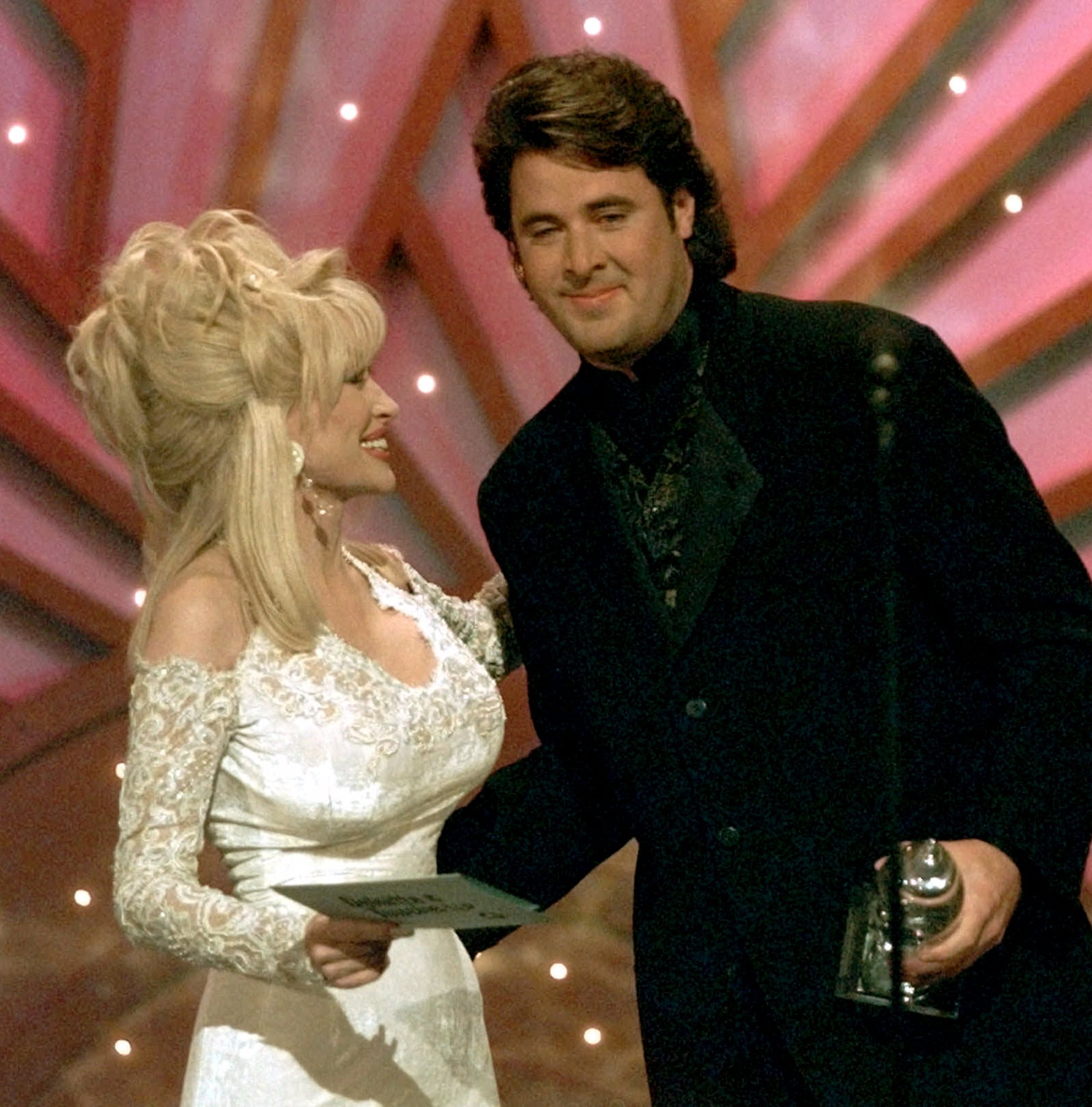 Vince Gill accepts his Song of the Year award from Dolly Parton during the Country Music Awards show in Nashville on Oct. 2, 1996.