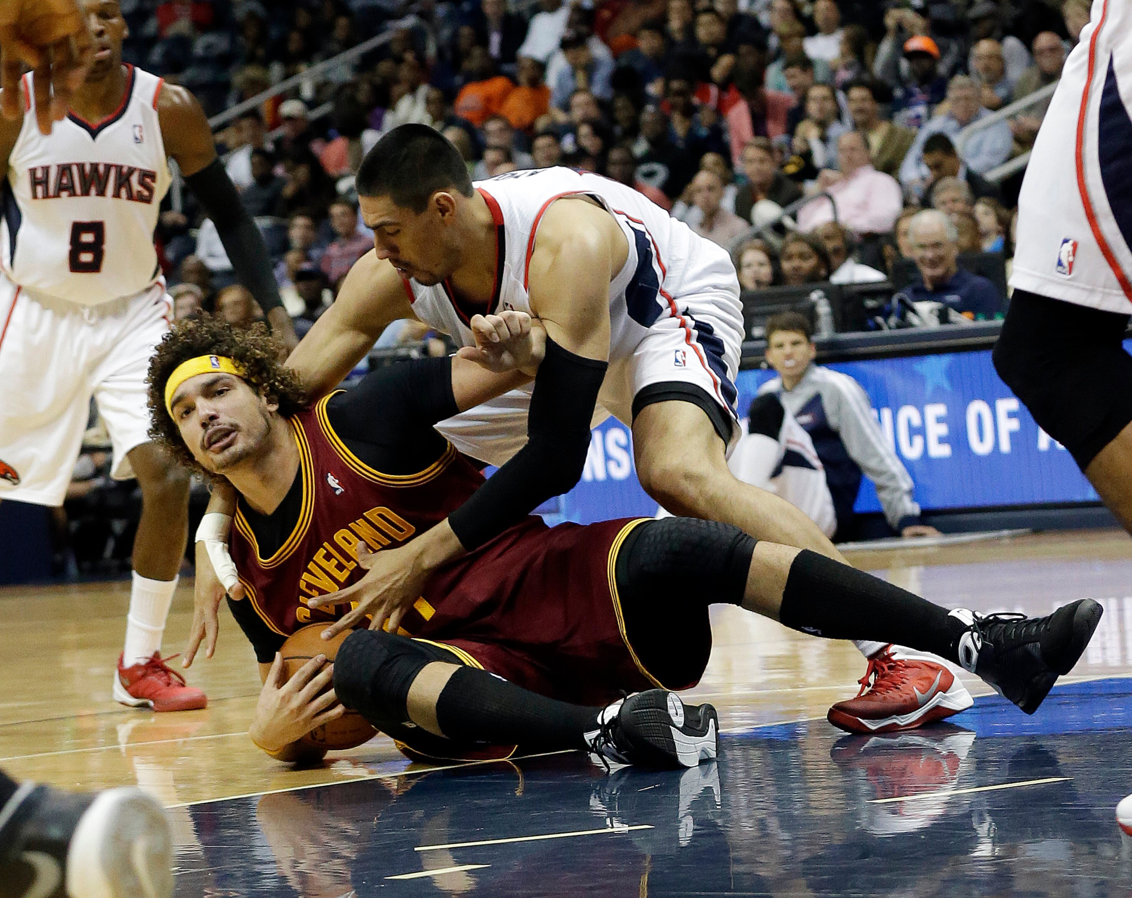 Cleveland Cavaliers center Anderson Varejao, left, and Atlanta Hawks forward Gustavo Ayon scramble for a loose ball in the second half of an NBA basketball game Friday, Dec. 6, 2013, in Atlanta.
