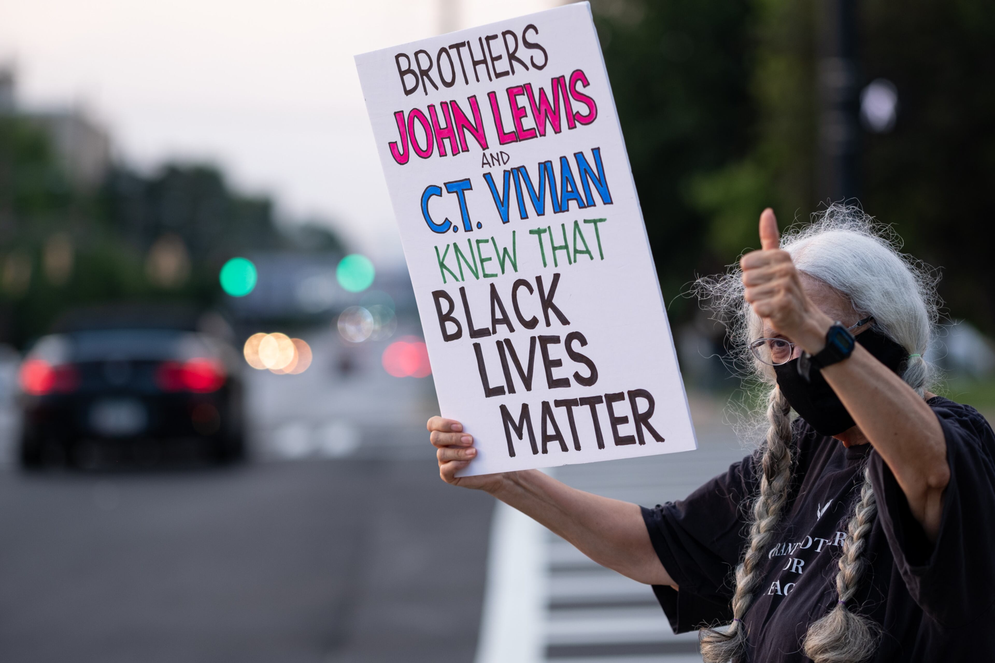 Lorraine Fontana holds a sign for passing drivers before a candlelight memorial and march in honor of the late U.S. Rep. John Lewis along John Lewis Freedom Parkway in Atlanta on Sunday, July 19, 2020. (Photo: Ben Gray for The Atlanta Journal-Constitution)