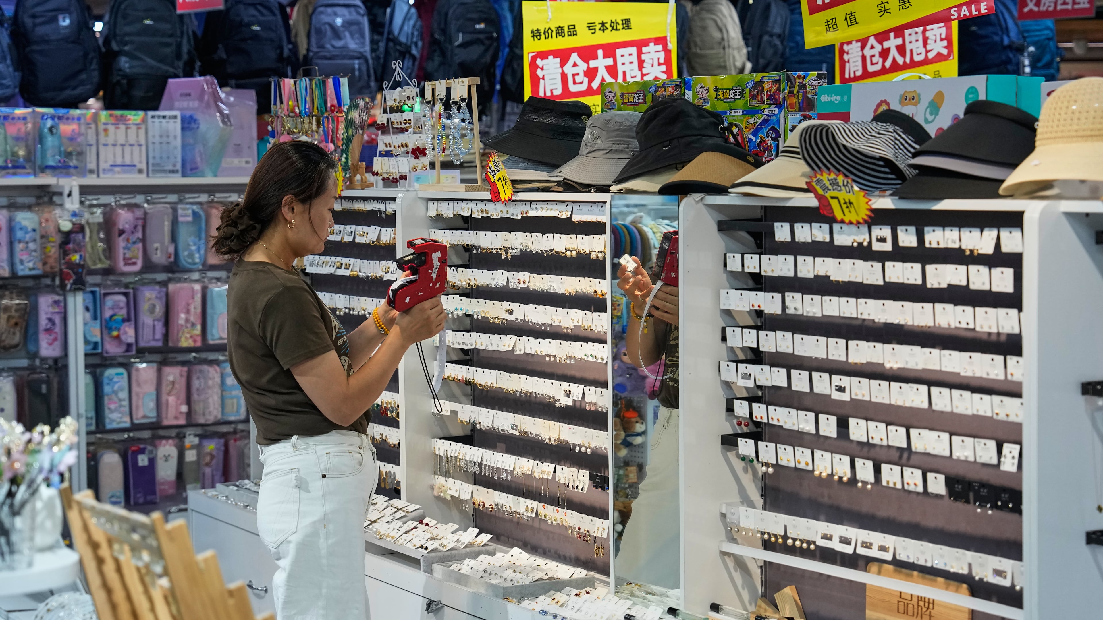A vendor puts price tag on the ear rings for sale at her store in Beijing, China on Wednesday, July 15, 2026. (AP Photo/Andy Wong)