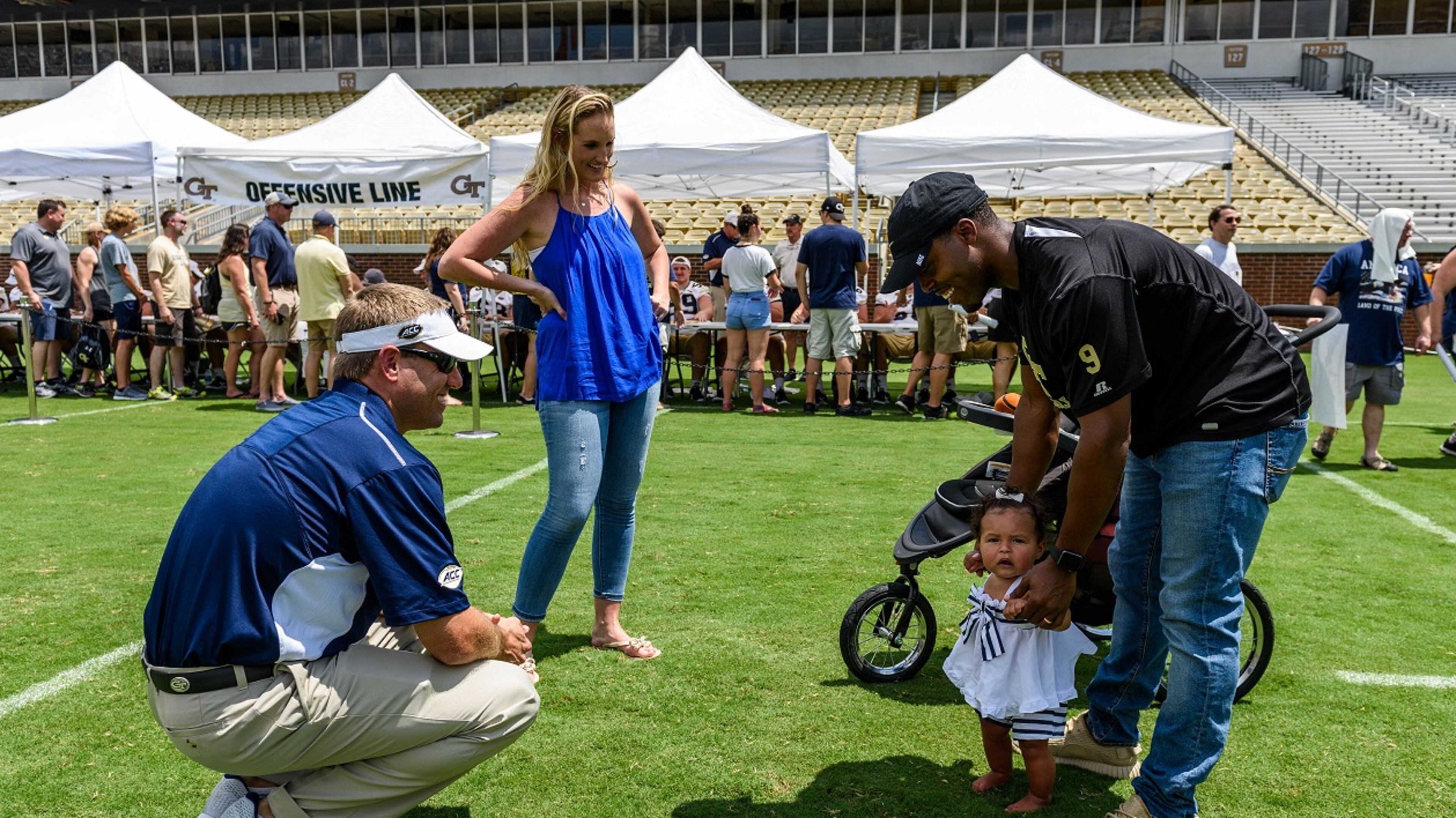 Georgia Tech quarterbacks/B-backs coach Craig Candeto (left) meets former Yellow Jackets A-back Tony Zenon's daughter Skyla (right), as Zenon and his wife, Abby, (center) looks on. They were taking part in Tech's Fan Day on Aug. 12, 2017 at Bobby Dodd Stadium. -- Danny Karnik/GT Athletics