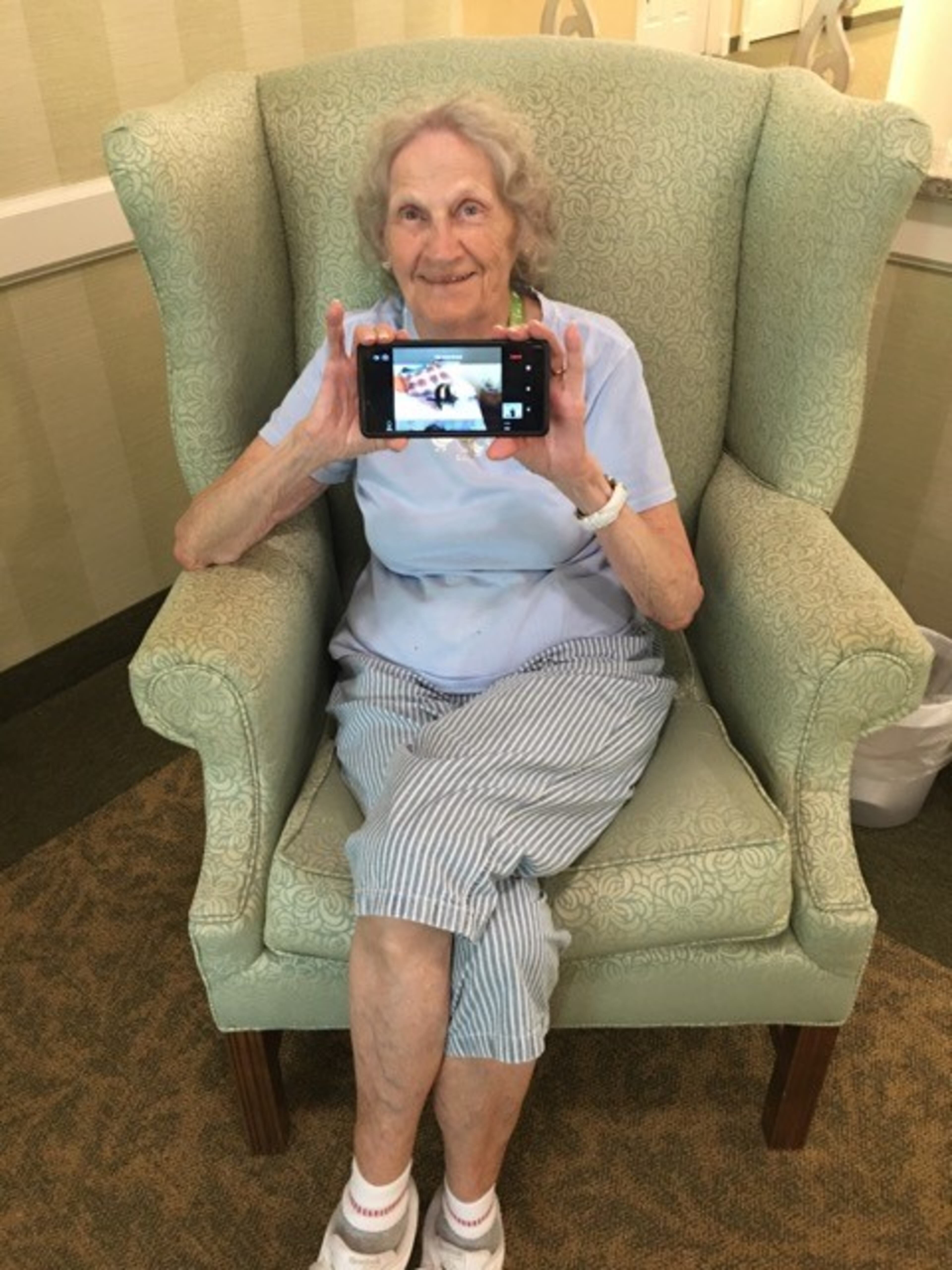 Brennity uses her phone to interact with pets and volunteers in her senior living community at Vero Beach, Florida. Pets Together is a free virtual pet visit being offered across the country to those living in group settings, such as nursing homes and senior living communities. Courtesy of Pets Together