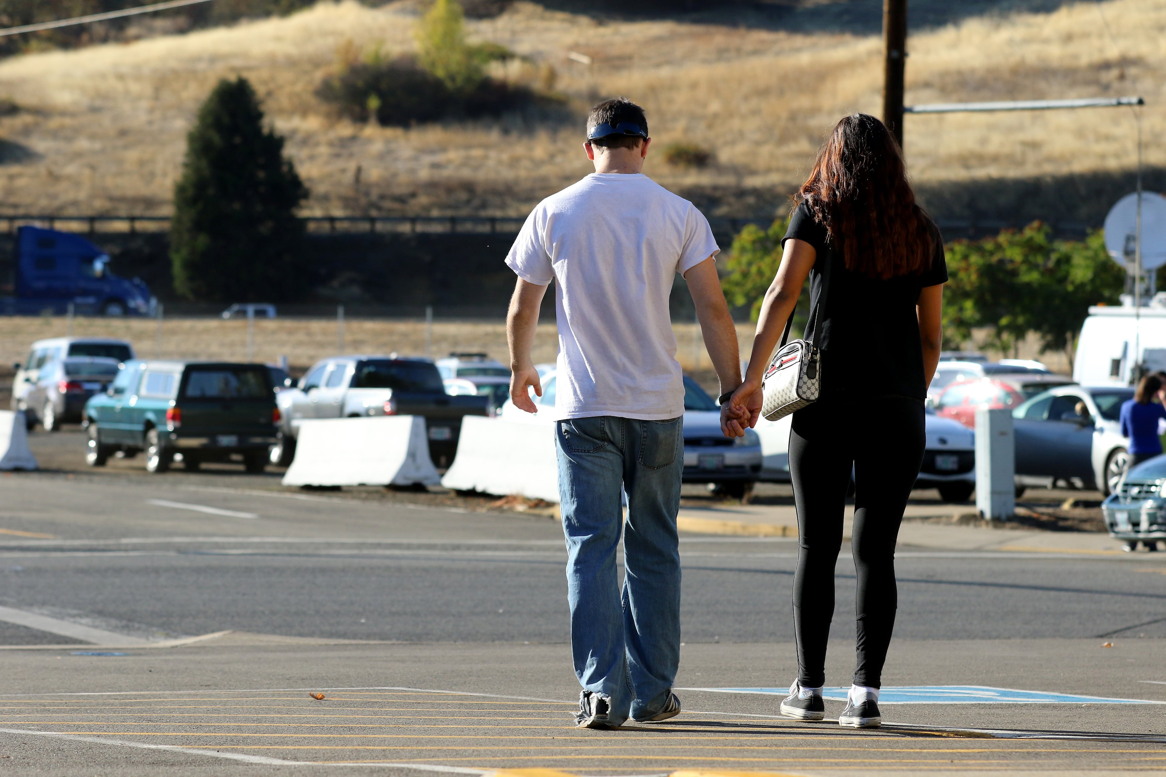 People hold hands they leave the county fairgrounds in Roseburg, Ore., Thursday, Oct. 1, 2015, following a deadly shooting at nearby Umpqua Community College. Students and faculty were bused to the fairgrounds where counselors were available and some parents waited for their children. (AP Photo/Ryan Kang)
