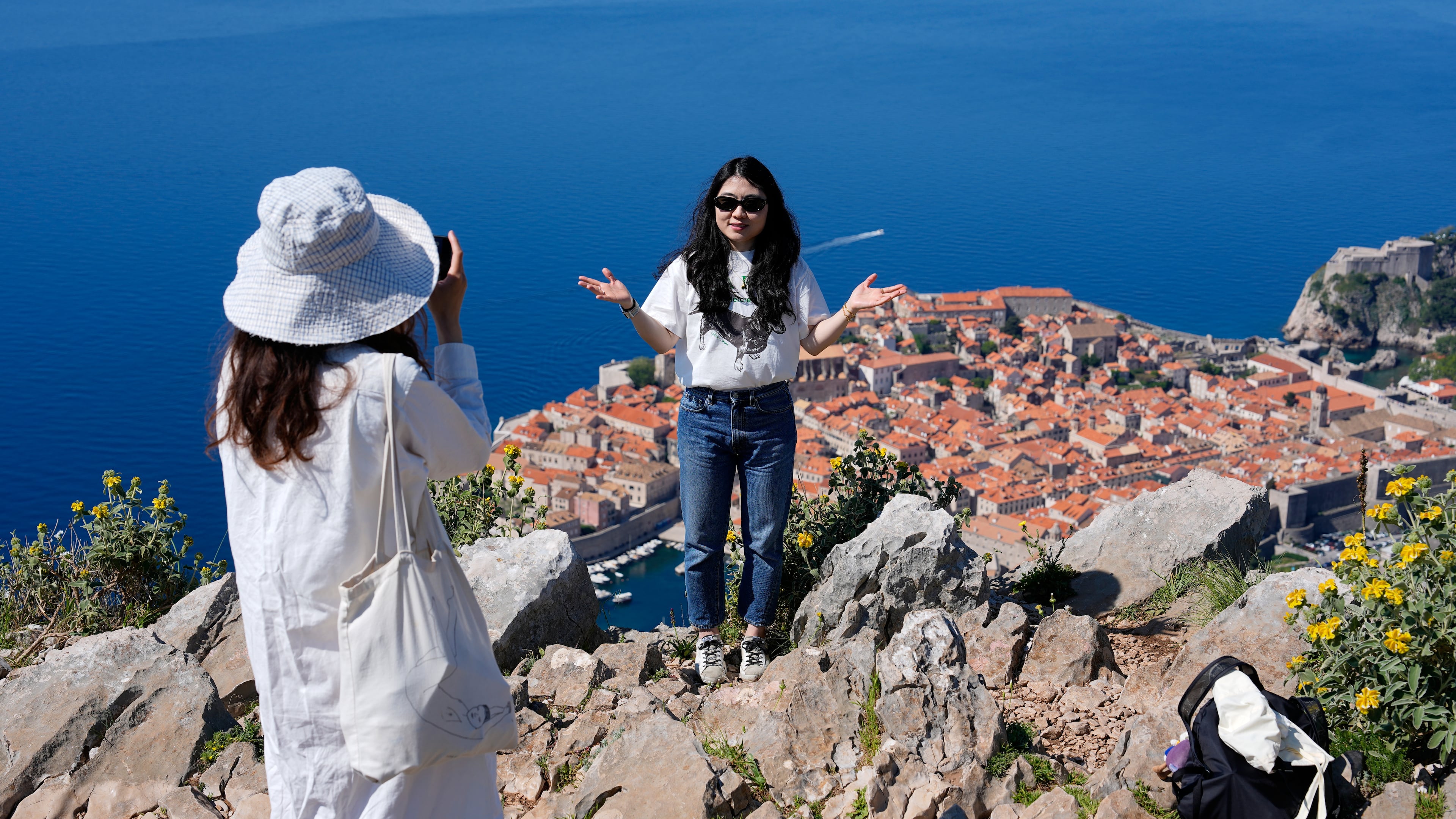 Tourists take photos of themselves on a hill overlooking the old town of Dubrovnik, Croatia, Monday, April 27, 2026. (AP Photo/Darko Bandic)