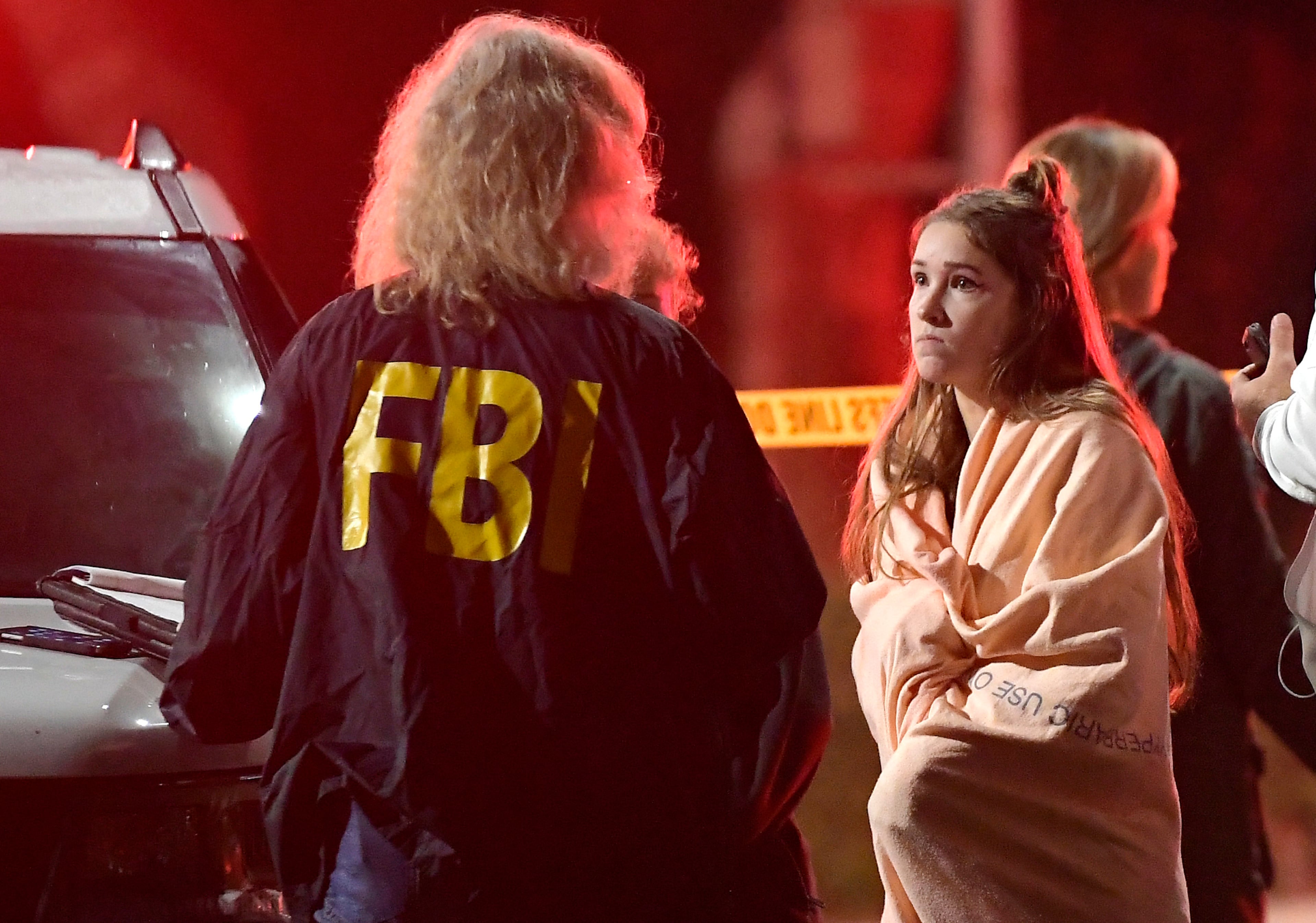 An FBI agent talks to a potential witness as they stand near the scene Thursday, Nov. 8, 2018, in Thousand Oaks, Calif. where a gunman opened fire Wednesday inside a country dance bar crowded with hundreds of people on "college night," wounding 11 people including a deputy who rushed to the scene. Ventura County sheriff's spokesman says gunman is dead inside the bar. (AP Photo/Mark J. Terrill)