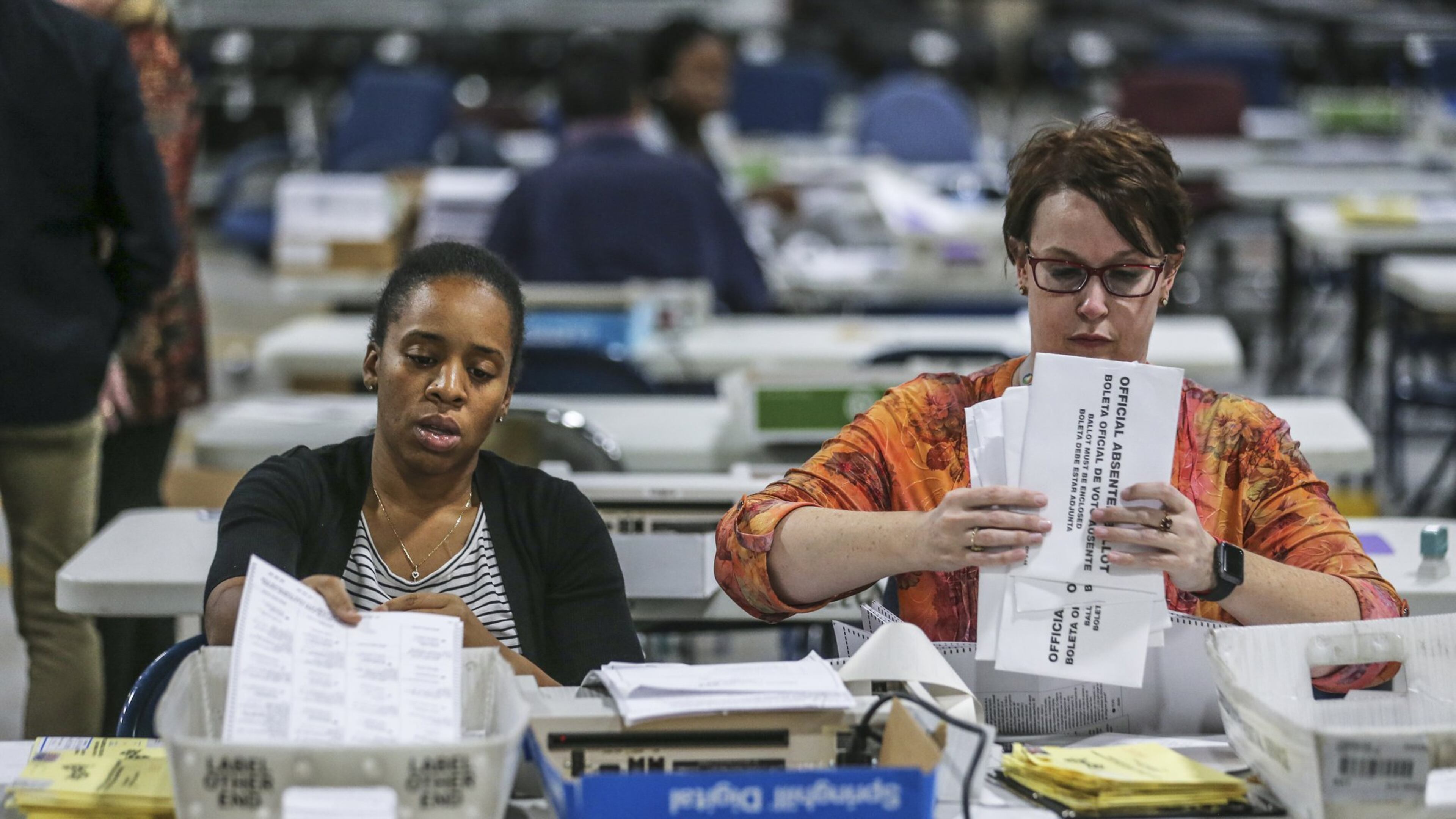 Elections Coordinator Shantell Black (left) and Elections Deputy Director Kristi Royston open and scan absentee ballots on Nov. 7, 2018 at the Voter Registration and Elections Office in Lawrenceville. JOHN SPINK/JSPINK@AJC.COM