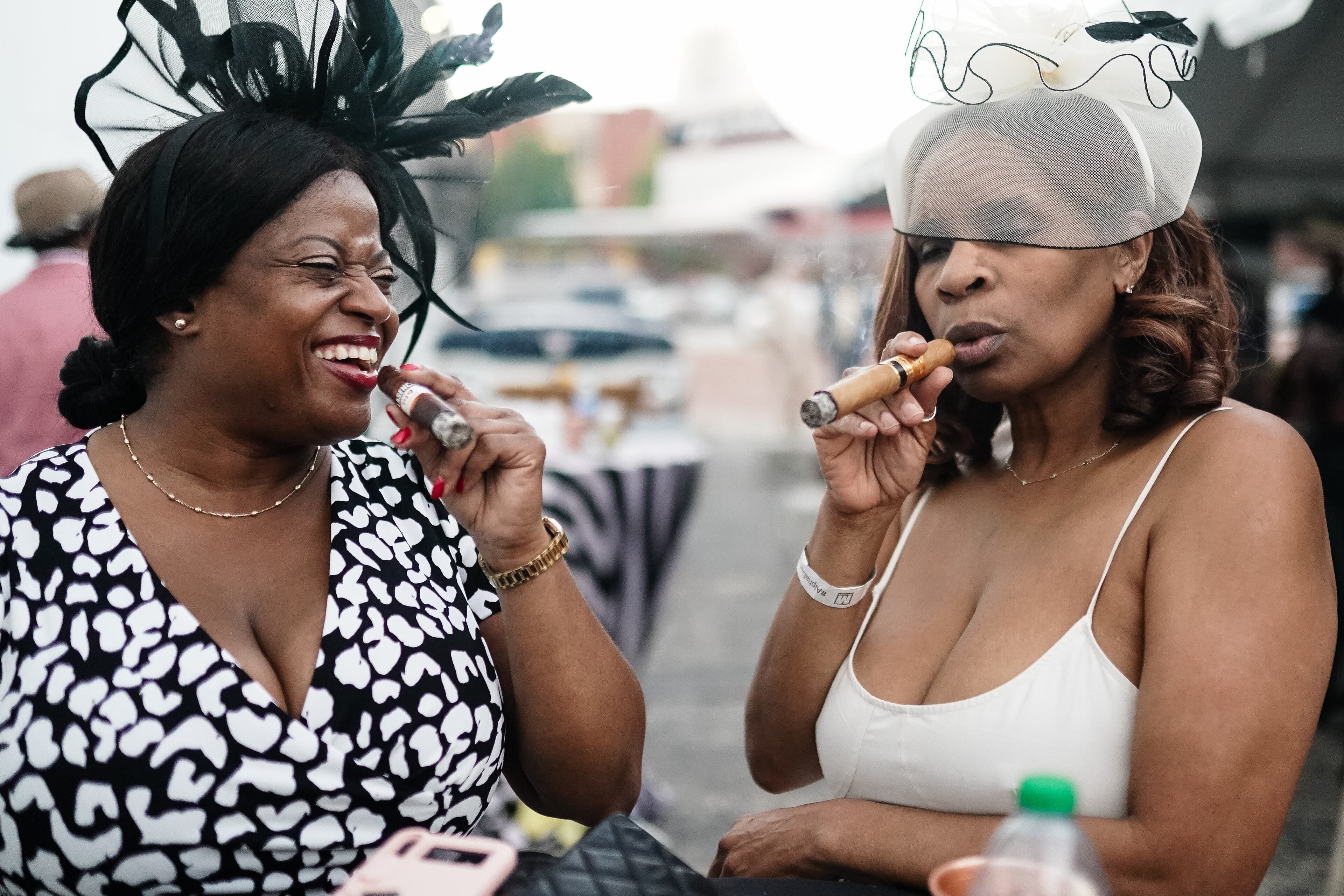 Tasha Dugger, left, and Daphne Ballard, right, smoke cigars at the Alpha Derby Kentucky Derby watch party at the Delta Flight Museum on Saturday, May 4, 2024, in Atlanta. (Elijah Nouvelage for The Atlanta Journal-Constitution)
