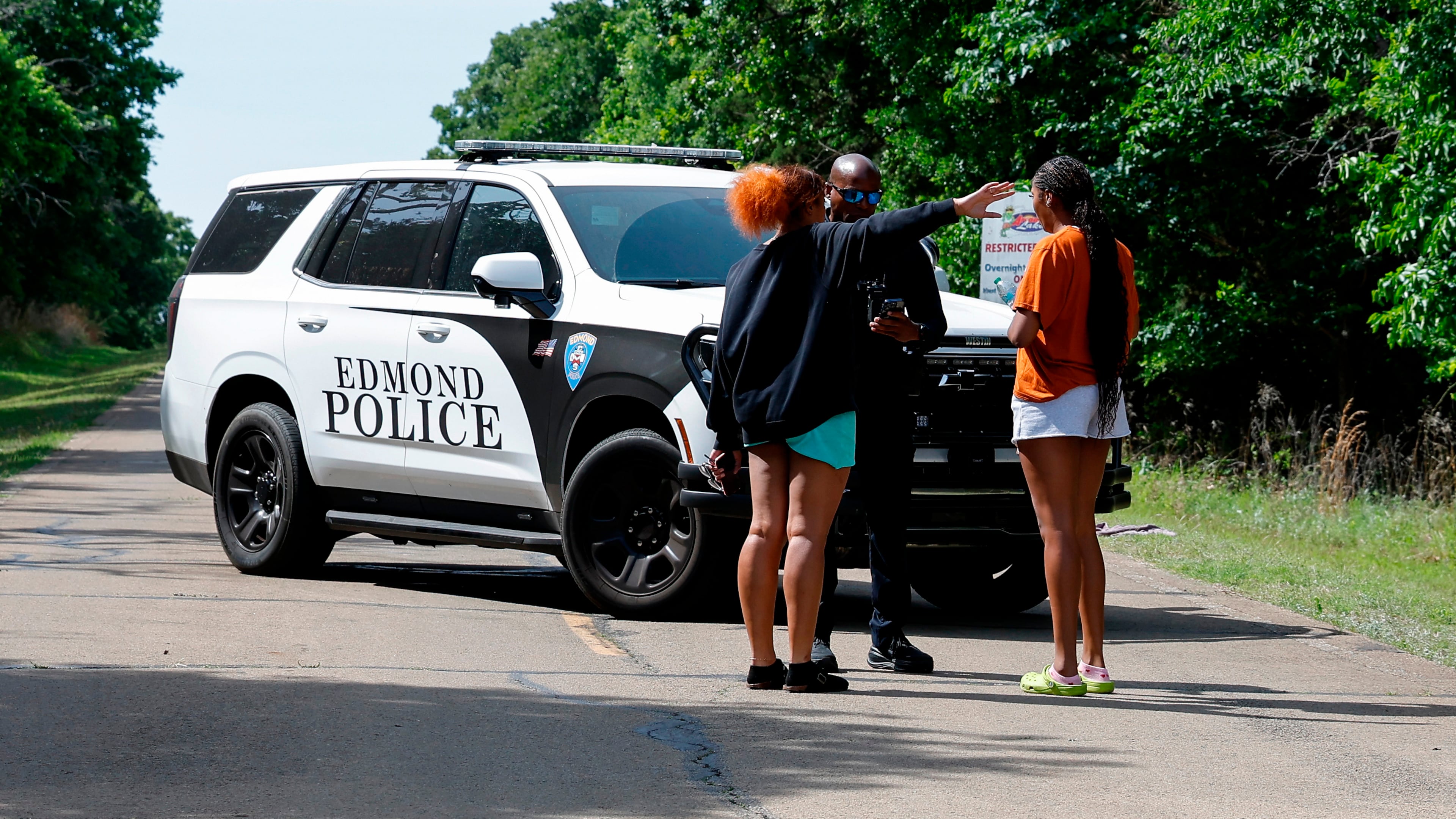 Two women talk to an Edmond police officer blocking the entrance to Scissortail Campground at Arcadia Lake, Monday, May 4, 2026, in Edmond, Okla., after a shooting on Sunday evening. (AP Photo/Alonzo Adams)