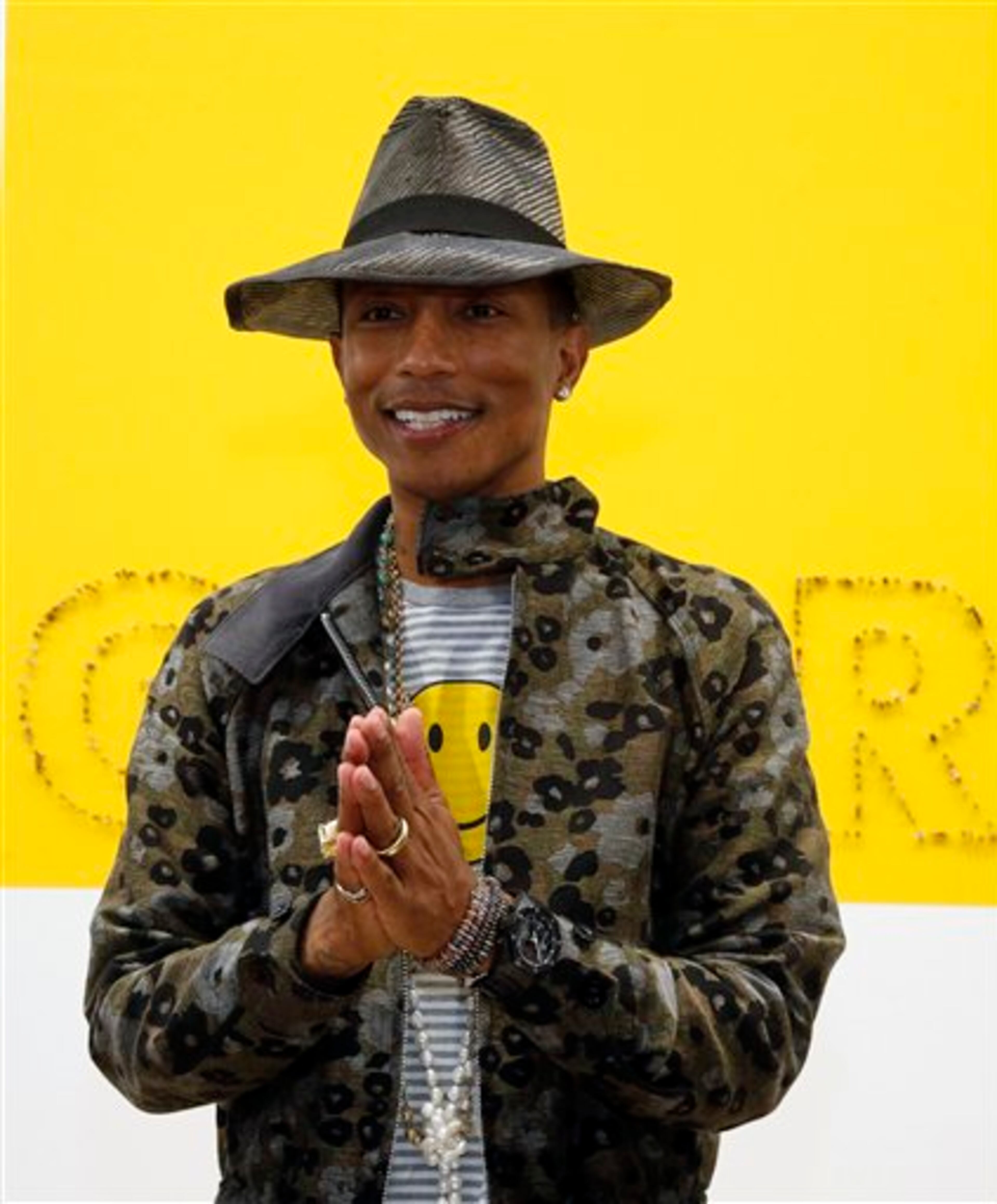 US singer Pharrell Williams poses during a press conference for the exhibition "GIRL" at the Perrotin Gallery in Paris, Monday, May 26, 2014. Williams curates an exhibition encompassing around 40 art pieces, presenting their visions of femininity, muses, female creativity and freedom. The show opens on May 27 and runs through June 27, 2014. The piece behind Williams is "GIRL" by French artist Guy Limone. (AP Photo/Francois Mori)