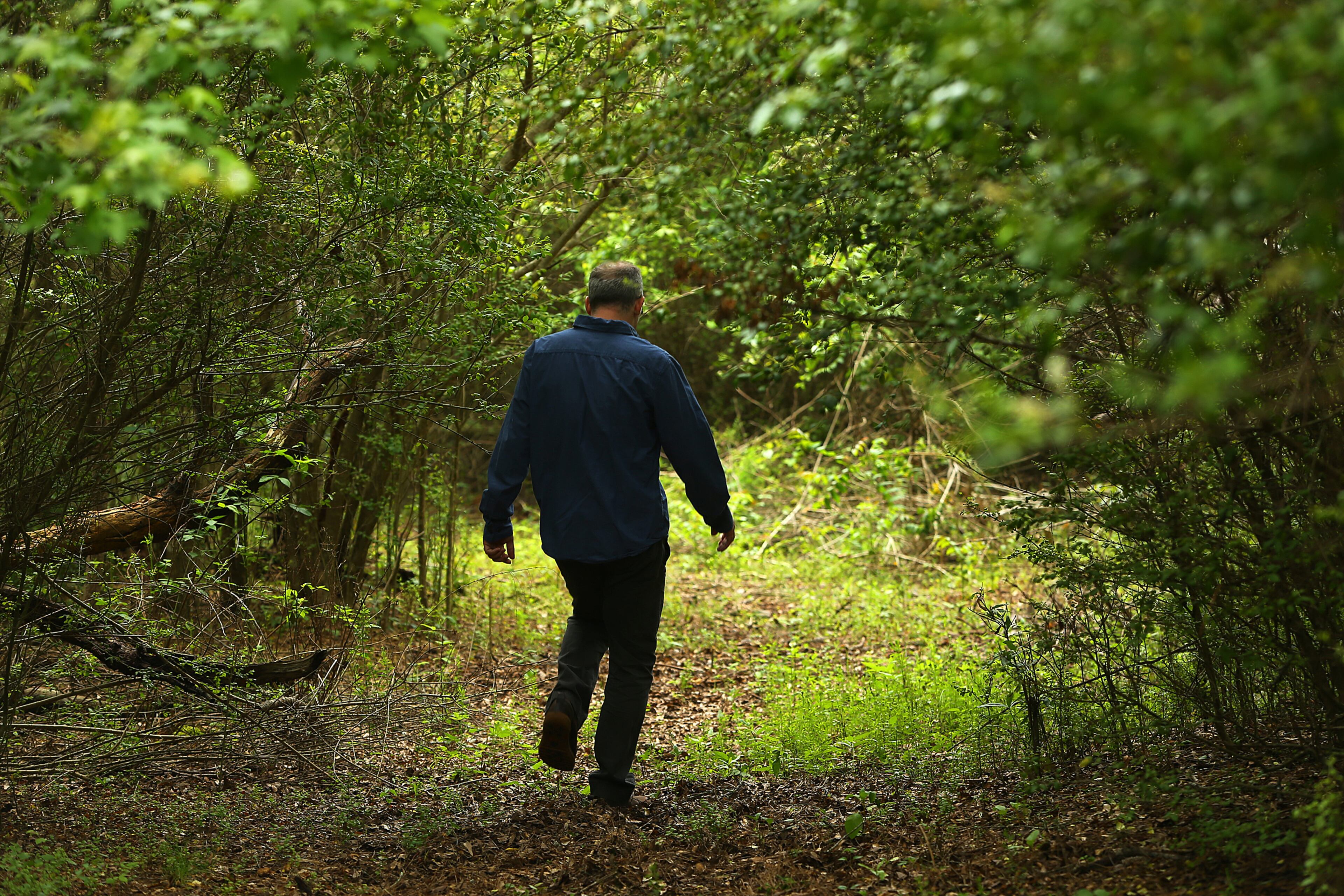 Paul Cooper walks a deer trail on the 50 acre farm of his grandmother Miss Besse Cooper on Monday, May 19, 2014, in Monroe. Cooper was the oldest person in the world until she died at the age of 116 years and 100 days in 2012. Her 50 acre farm has been in the family since 1926 making for a dispute among her heirs on whether to sell the property. Paul Cooper wants to see the property turned into a park. CURTIS COMPTON / CCOMPTON@AJC.COM