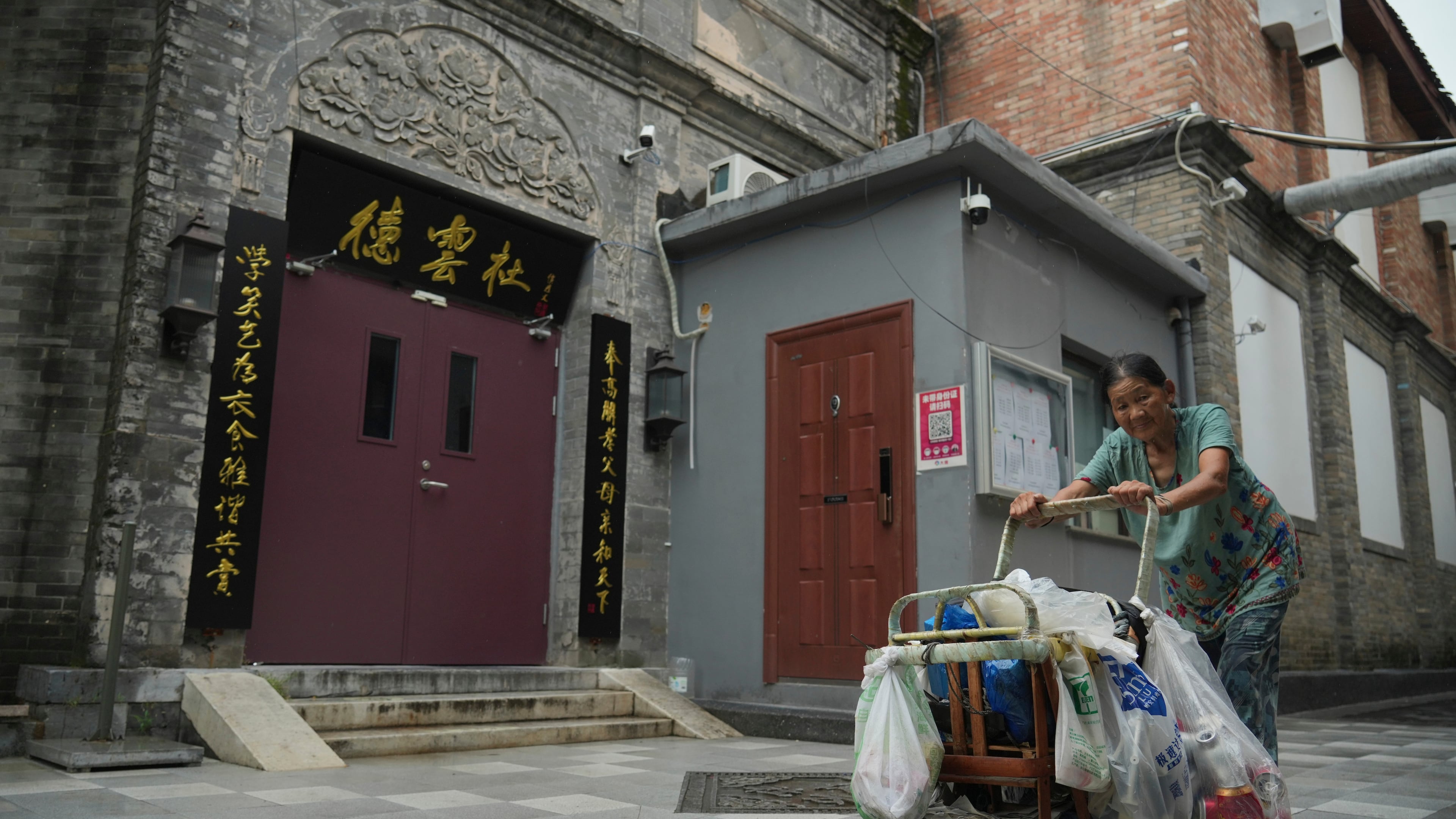 A woman pushes a cart past a Deyunshe theater, part of the comedy group founded by Guo Degang, in Beijing, Saturday, Aug. 22, 2026. (AP Photo/Achmad Ibrahim)