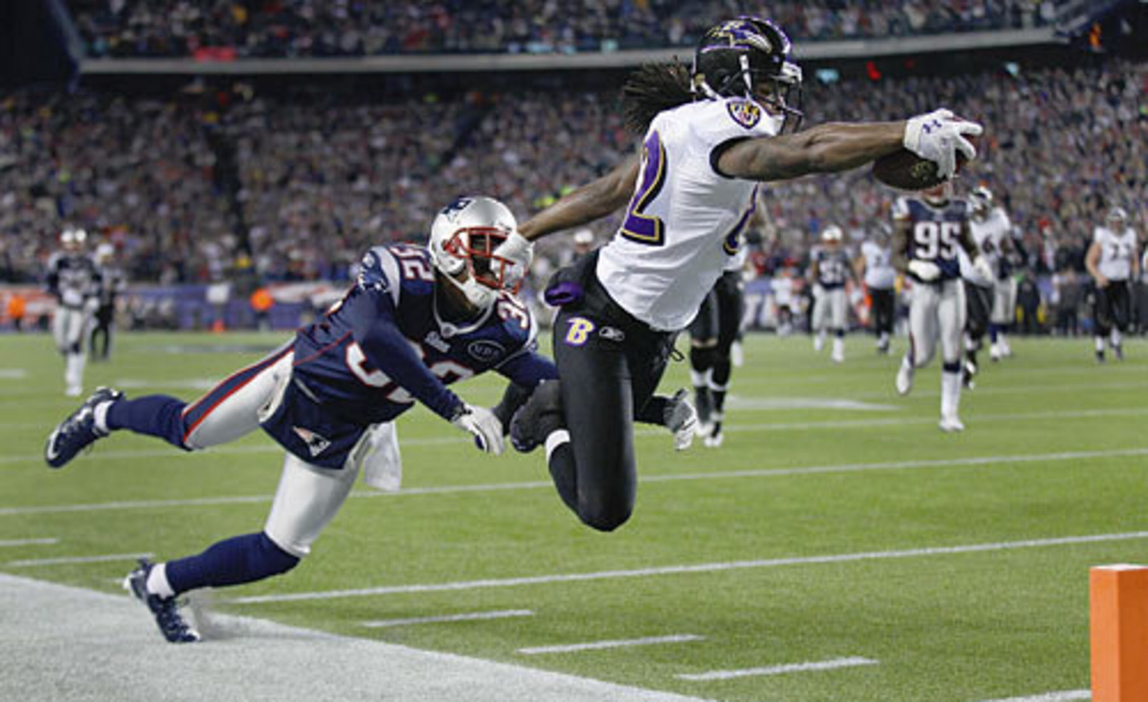 Ravens wide receiver Torrey Smith (82) dives into the end zone for a touchdown as Patriots cornerback Devin McCourty (32) hangs on during the second half.