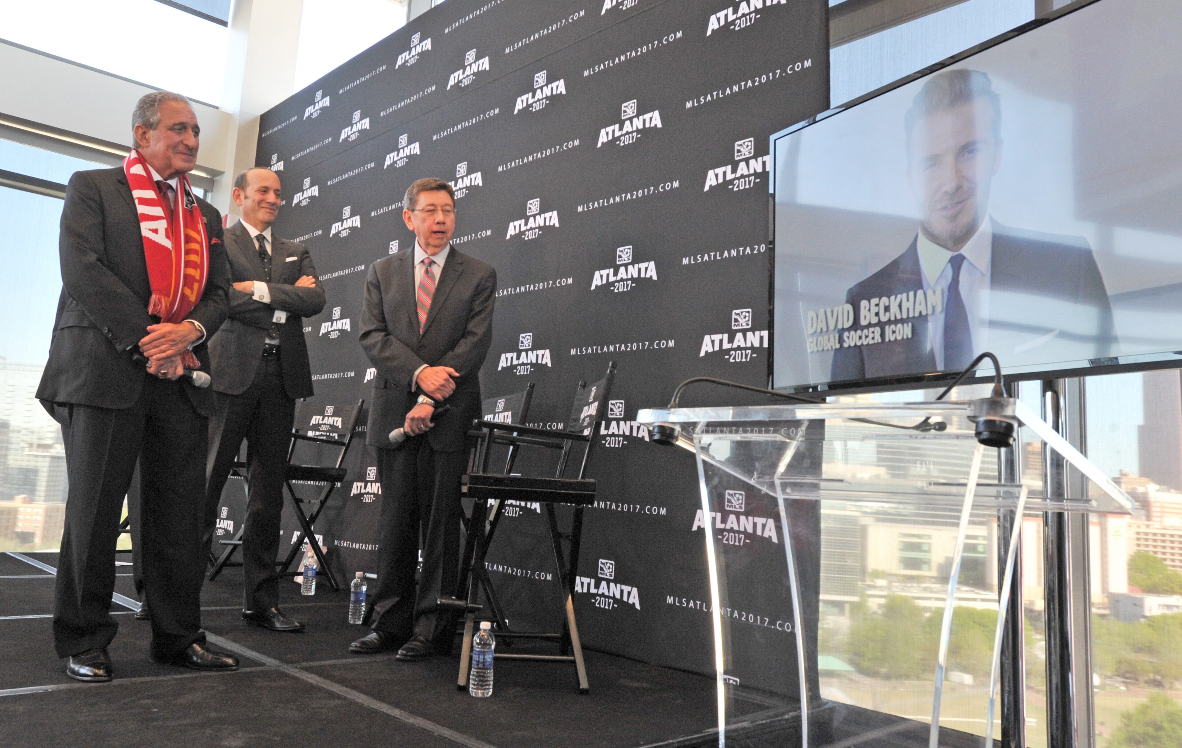 Falcons owner Arthur Blank, MLS commissioner Don Garber and executive director of GWCC Frank Poe watch congratulatory message from soccer star David Beckham during the official announcement event in downtown Atlanta on Wednesday, April 16, 2014. HYOSUB SHIN / HSHIN@AJC.COM