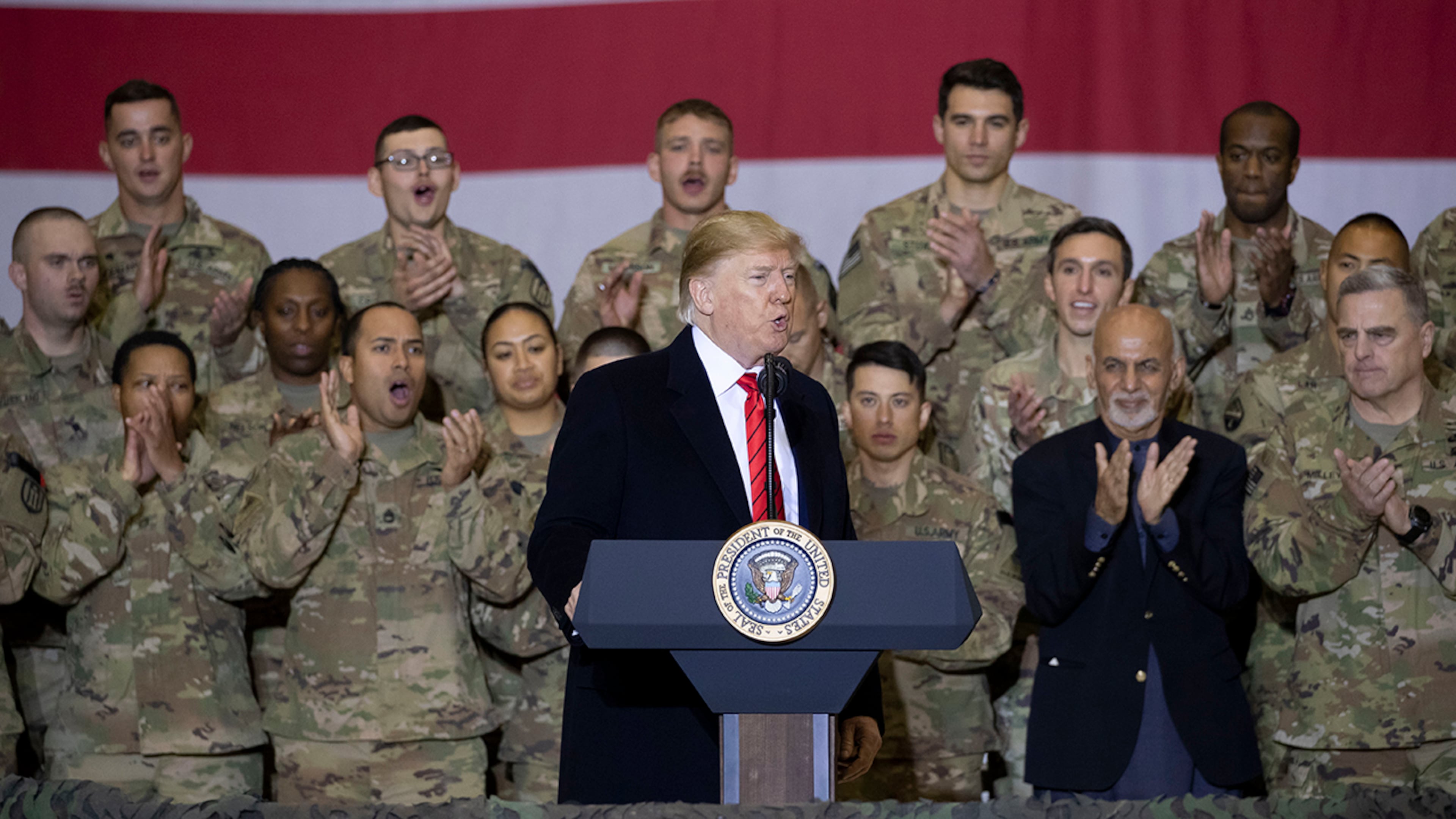 President Donald Trump, center, with Afghan President Ashraf Ghani, second from the right, and Joint Chiefs Chairman Gen. Mark Milley, right, while addressing members of the military during a surprise Thanksgiving Day visit, Thursday, Nov. 28, 2019, at Bagram Air Field, Afghanistan. (AP Photo/Alex Brandon)