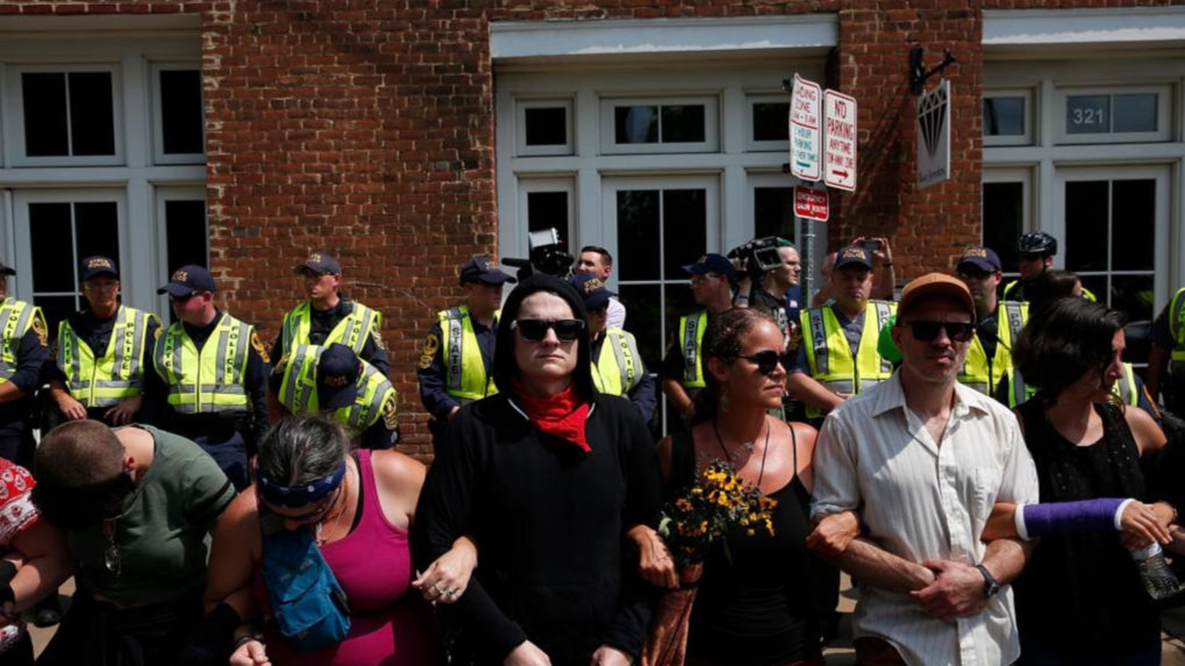 Members of the Charlottesville community and protest groups locked arms in front of police on Aug. 12. The next day, the organizer of a Unite the Right rally was punched by a man when he attempted to make a speech.