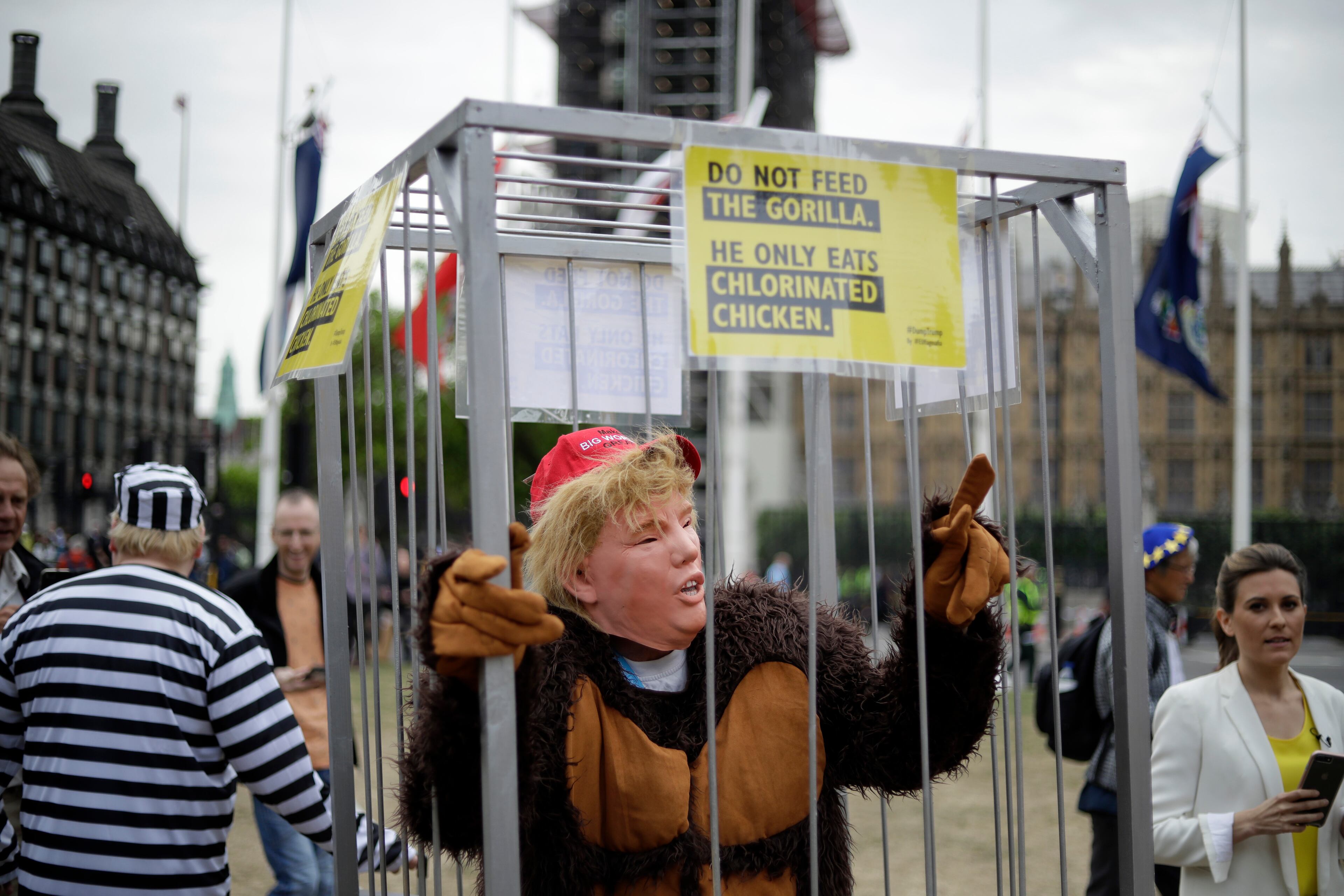 Man in a mask stands in a cage as people start to gather to demonstrate against the state visit of President Donald Trump in Parliament Square, central London, Tuesday, June 4, 2019. Trump will turn from pageantry to policy Tuesday as he joins British Prime Minister Theresa May for a day of talks likely to highlight fresh uncertainty in the allies' storied relationship. (AP Photo/Matt Dunham)