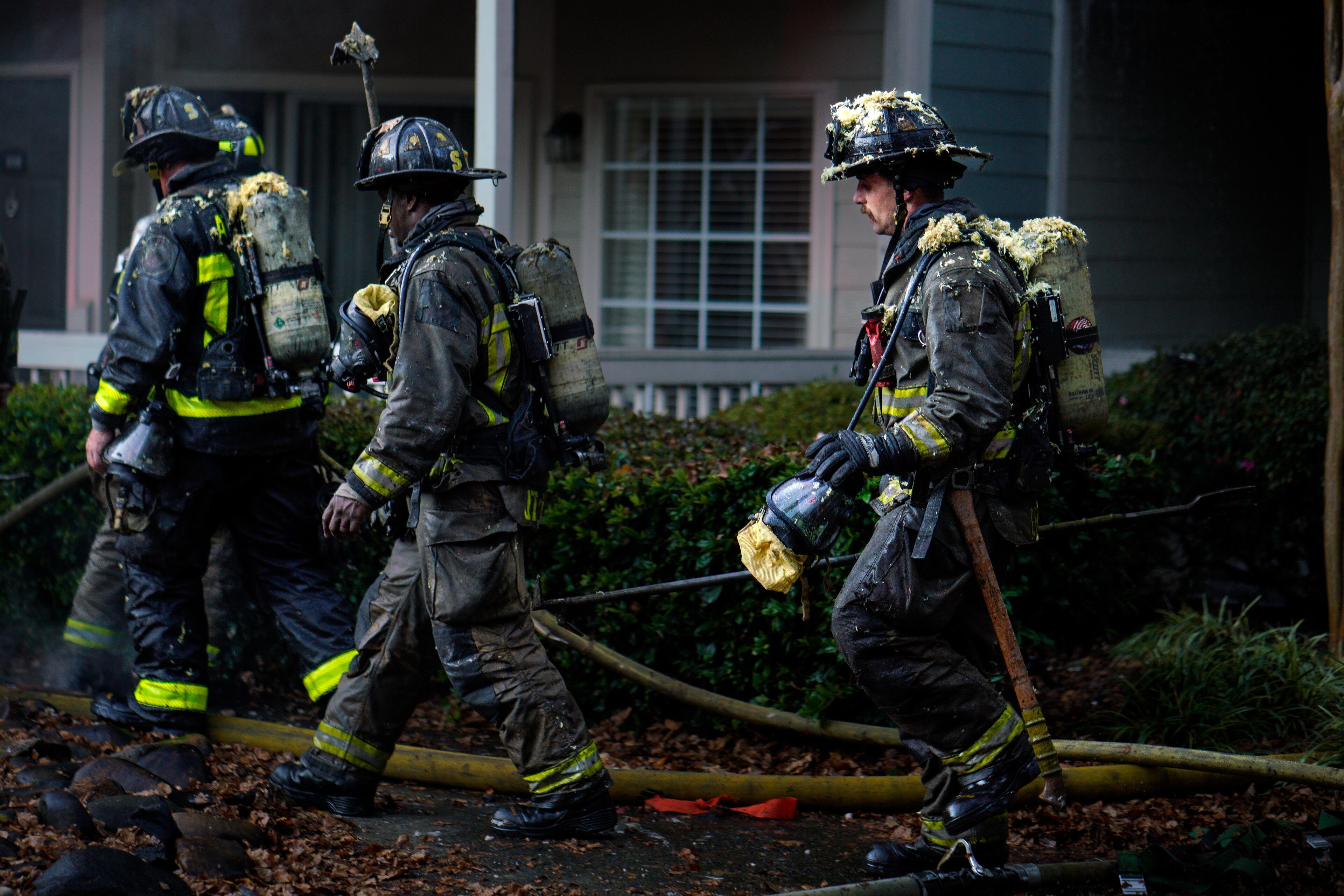 Atlanta firefighters covered in debris exit an apartment fire on Cityline Avenue in downtown Atlanta on Monday. (Ben Hendren for the Atlanta Journal-Constitution)