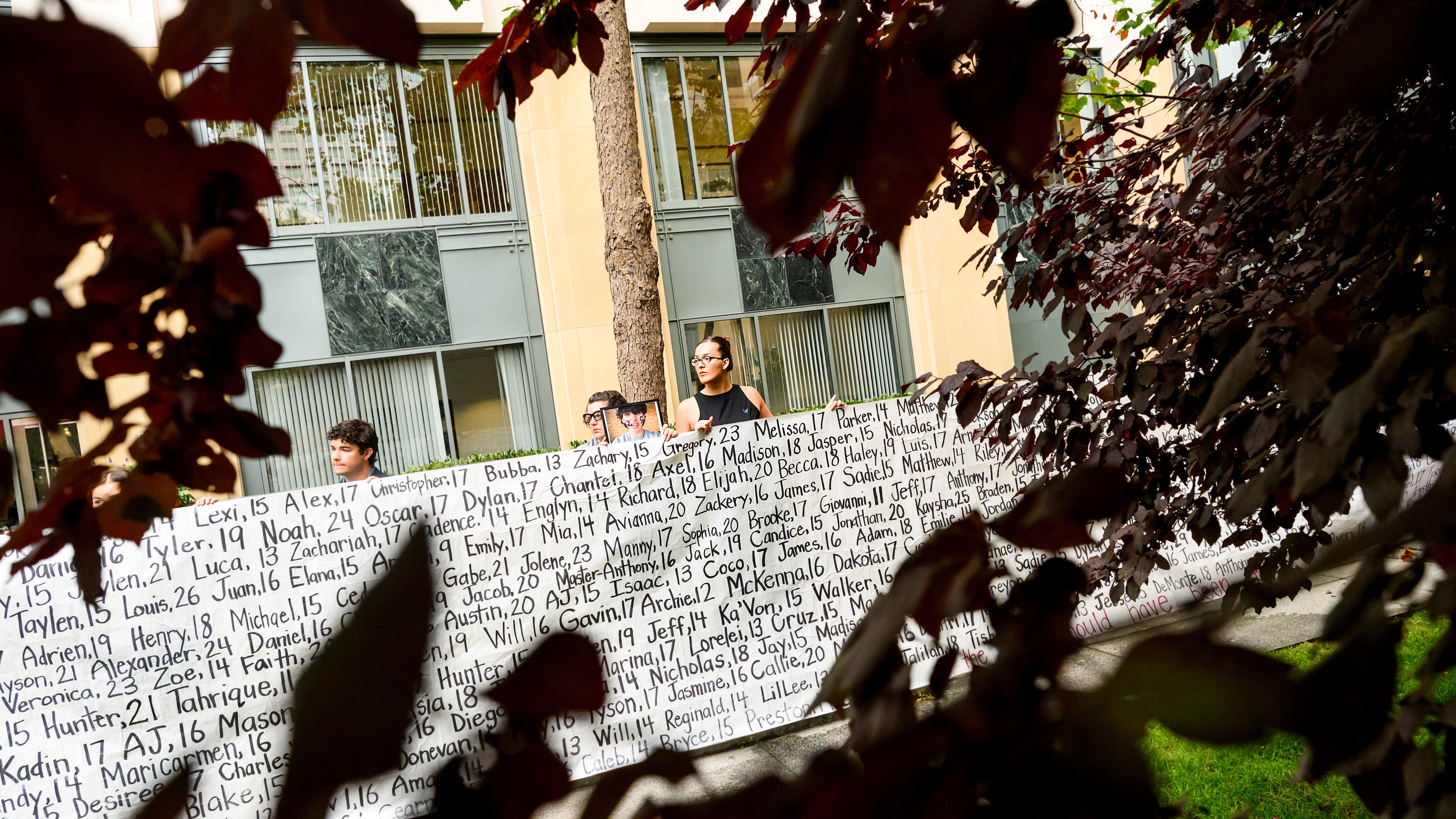 Lennon Torres of Heat Initiative holds a banner with names of young people who advocates say died as a result of social media outside the Ronald V. Dellums Federal Building and U.S. Courthouse on Tuesday, Aug. 18, 2026, in Oakland, Calif. (AP Photo/Noah Berger)