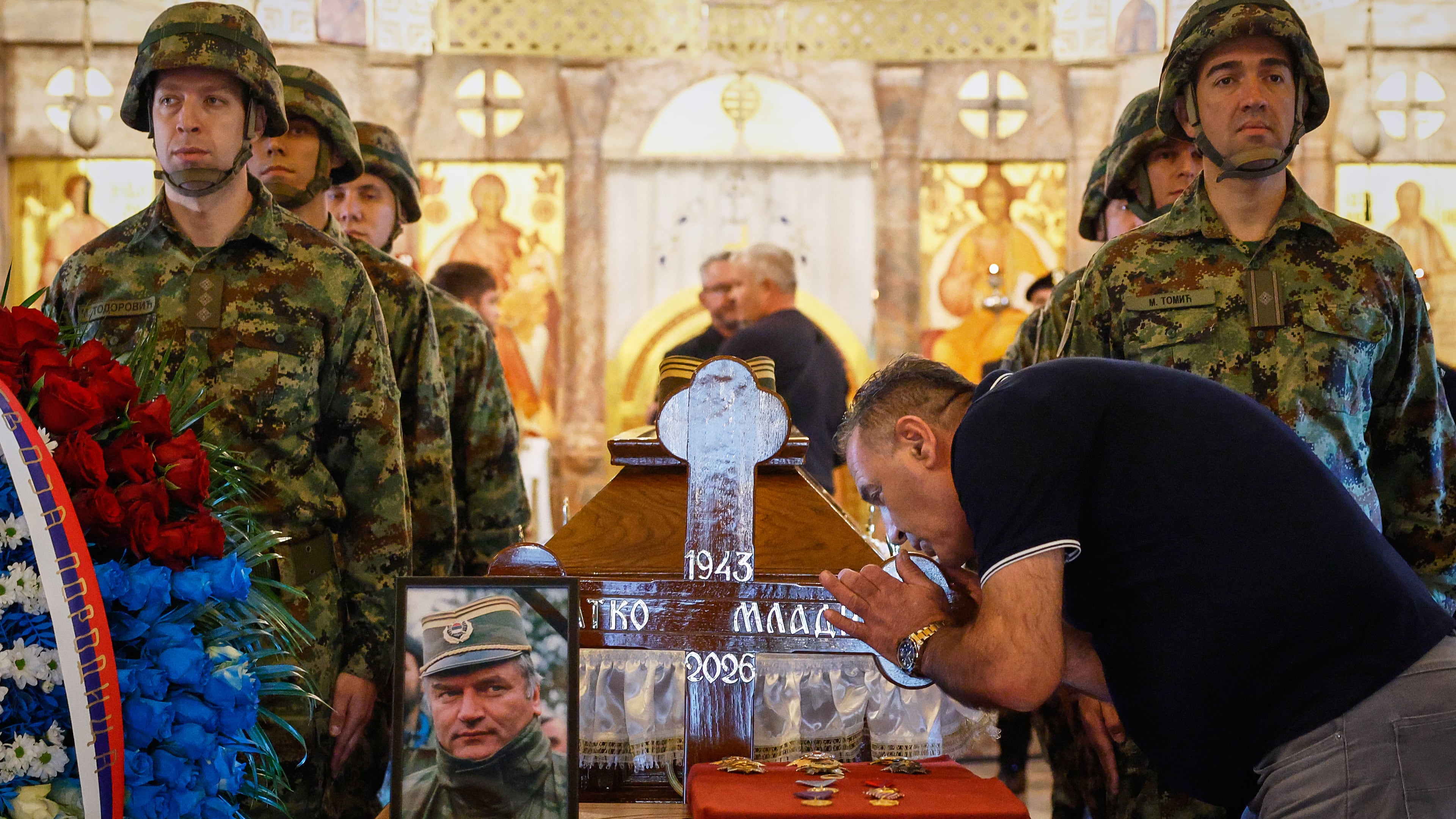 A man touches the cross as Serbian national military servicemen stand around the coffin of the former Bosnian Serb army commander Ratko Mladic, who died last week while serving a life sentence for genocide and other atrocities during the war in Bosnia, at the St. Luka Church, in Belgrade, Serbia, Monday, Sept. 7, 2026. (AP Photo/Marko Drobnjakovic)