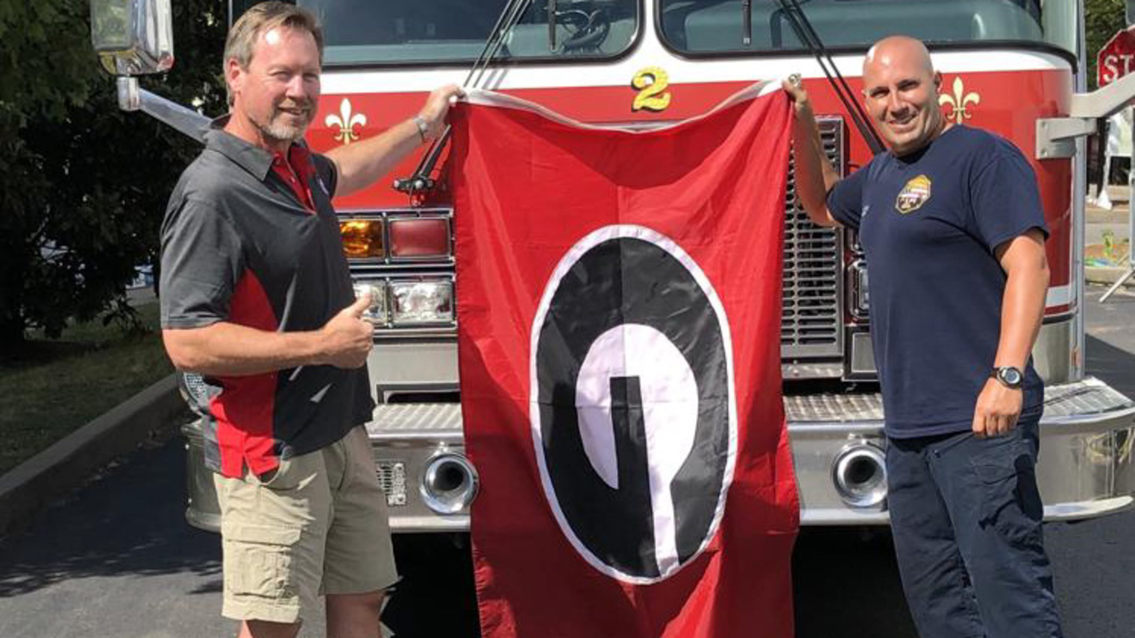 Joe Purcell (L) of Athens was more than happy to donate his “G Flag” to Nashville firefighter Justin Champion to fly on his Rescue 2 firetruck. (Chip Towers/ctowers@ajc.com)