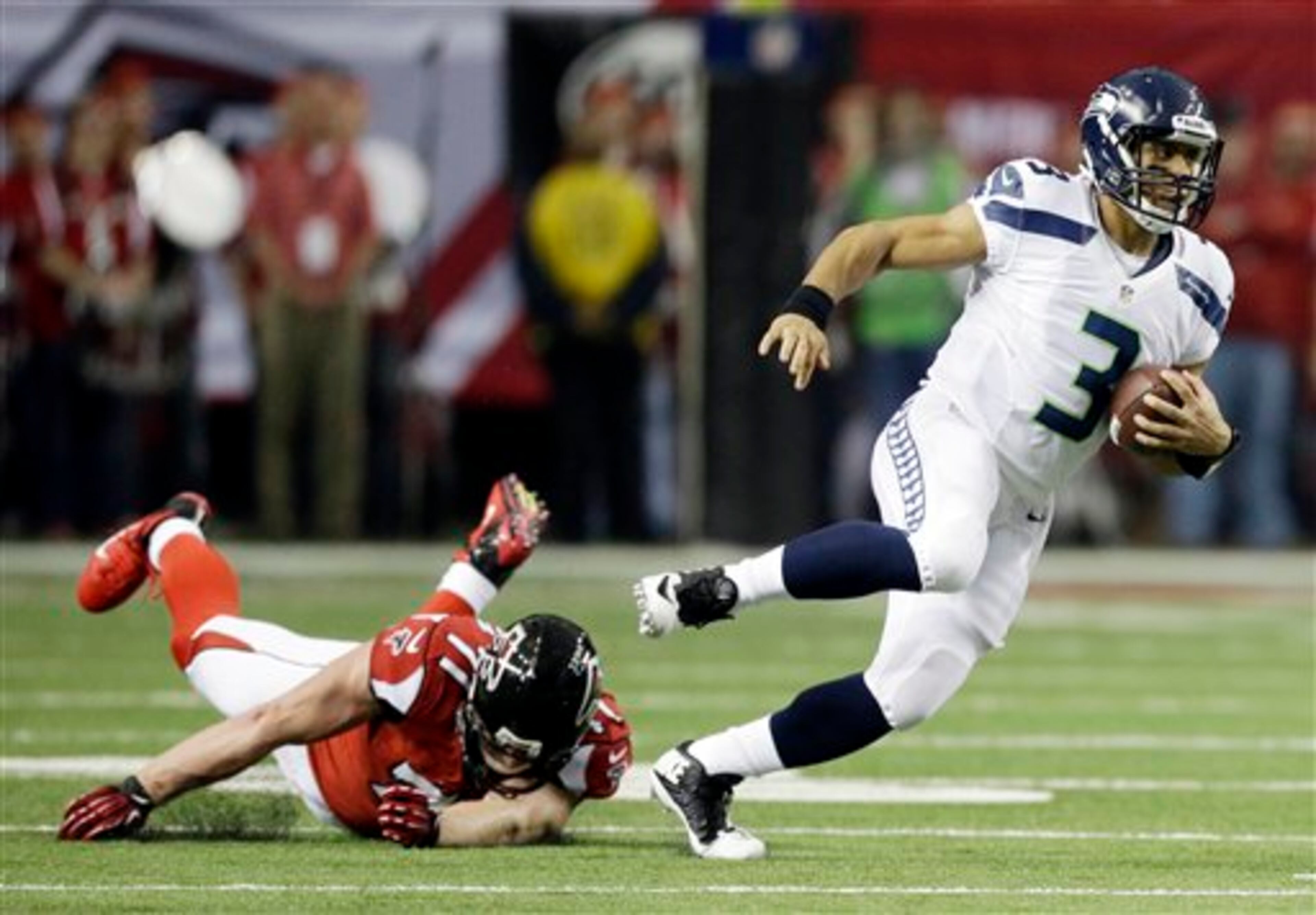 Seattle Seahawks quarterback Russell Wilson (3) runs past Atlanta Falcons defensive end Kroy Biermann (71) during the first half of an NFC divisional playoff NFL football game Sunday, Jan. 13, 2013, in Atlanta. (AP Photo/David Goldman)