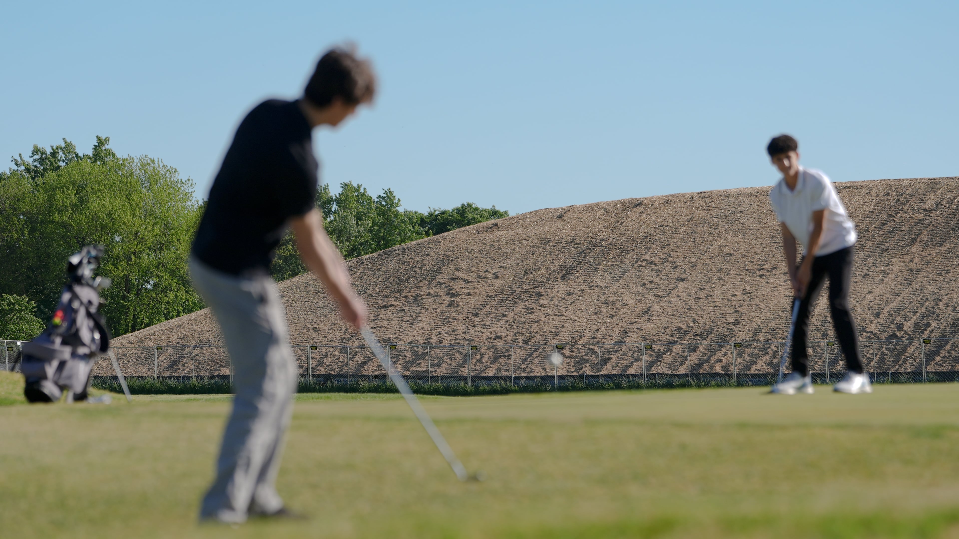 A pile of debris is seen in the background as Roman Sandoli, right, prepares to putt at the East Potomac Golf Course, Sunday, May 3, 2026, in Washington. (AP Photo/Julia Demaree Nikhinson)