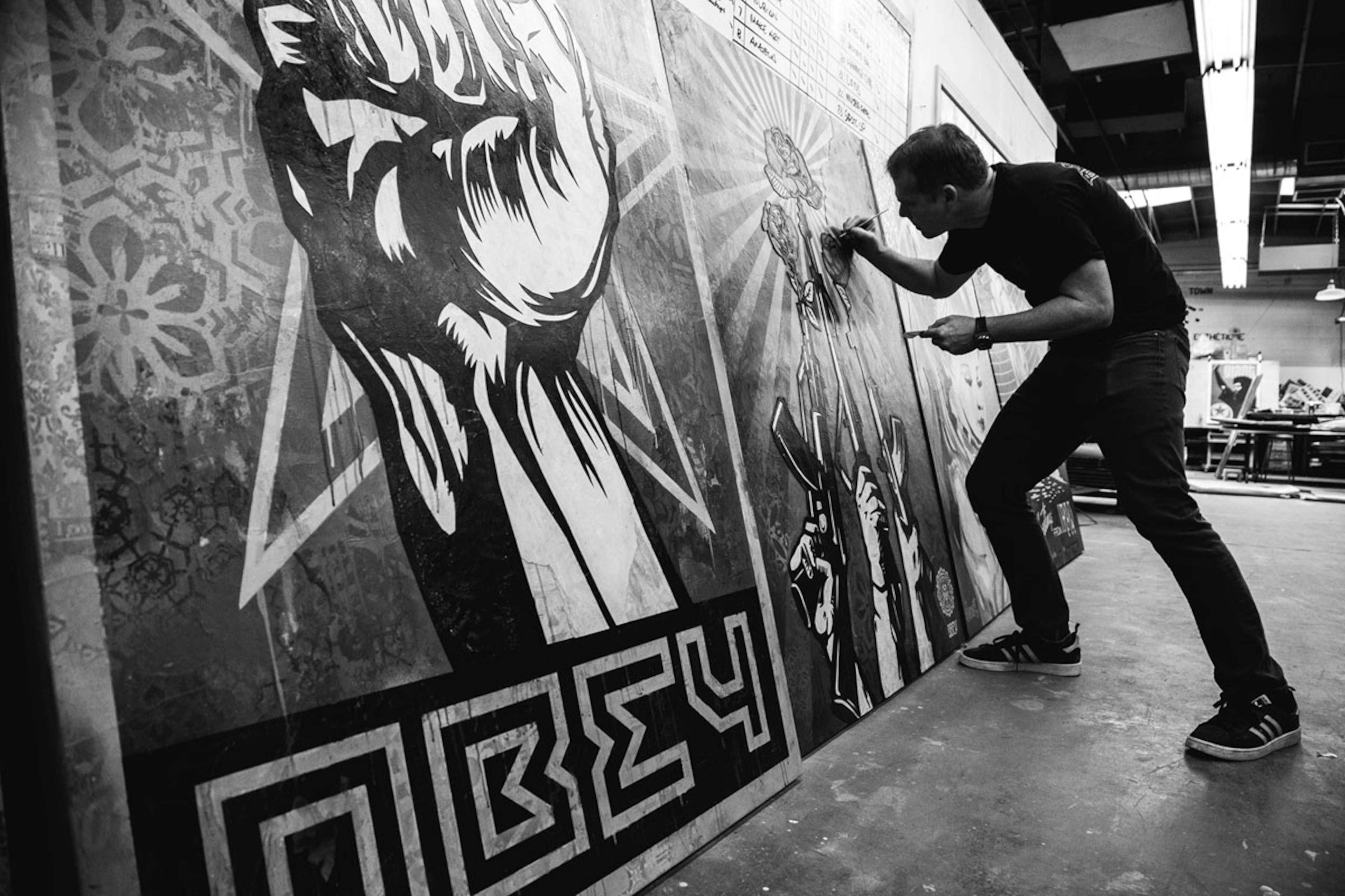 Fairey leans into an oversized painting in progress. (Courtesy of ABV Gallery)